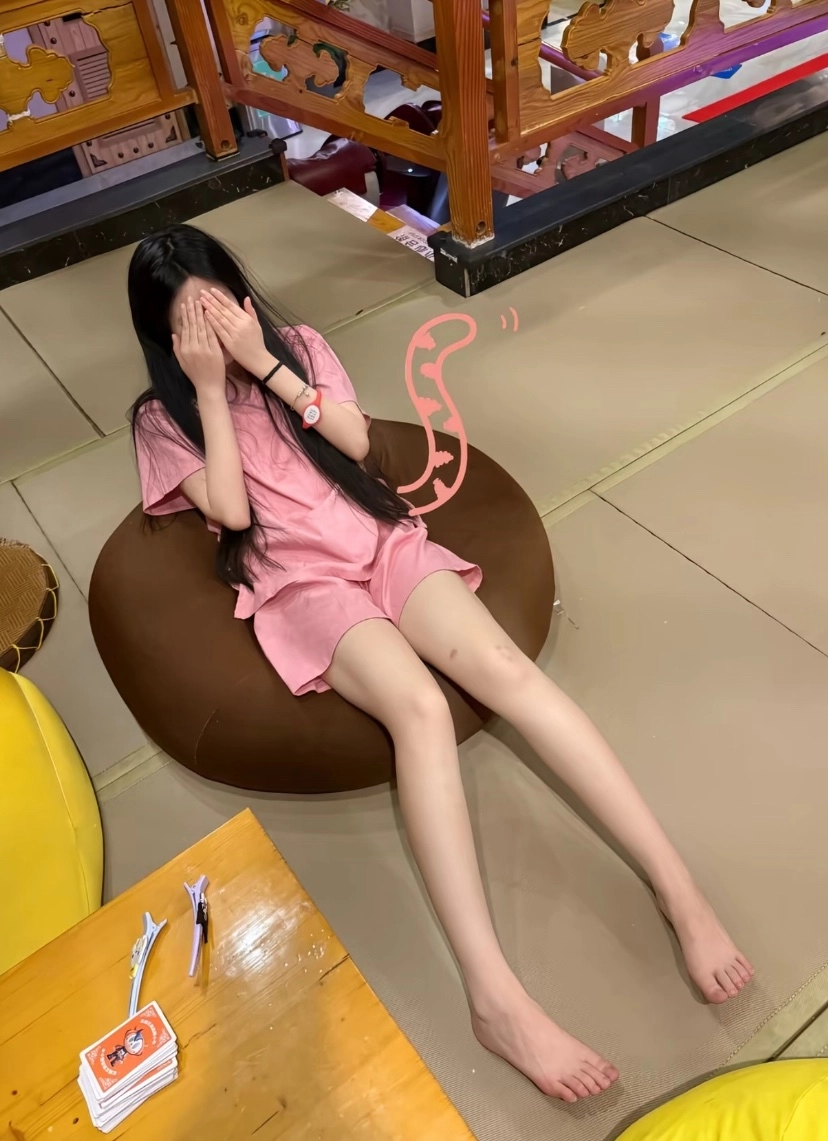 长头发和粉红色衬衫的女孩坐在一把豆袋椅上。