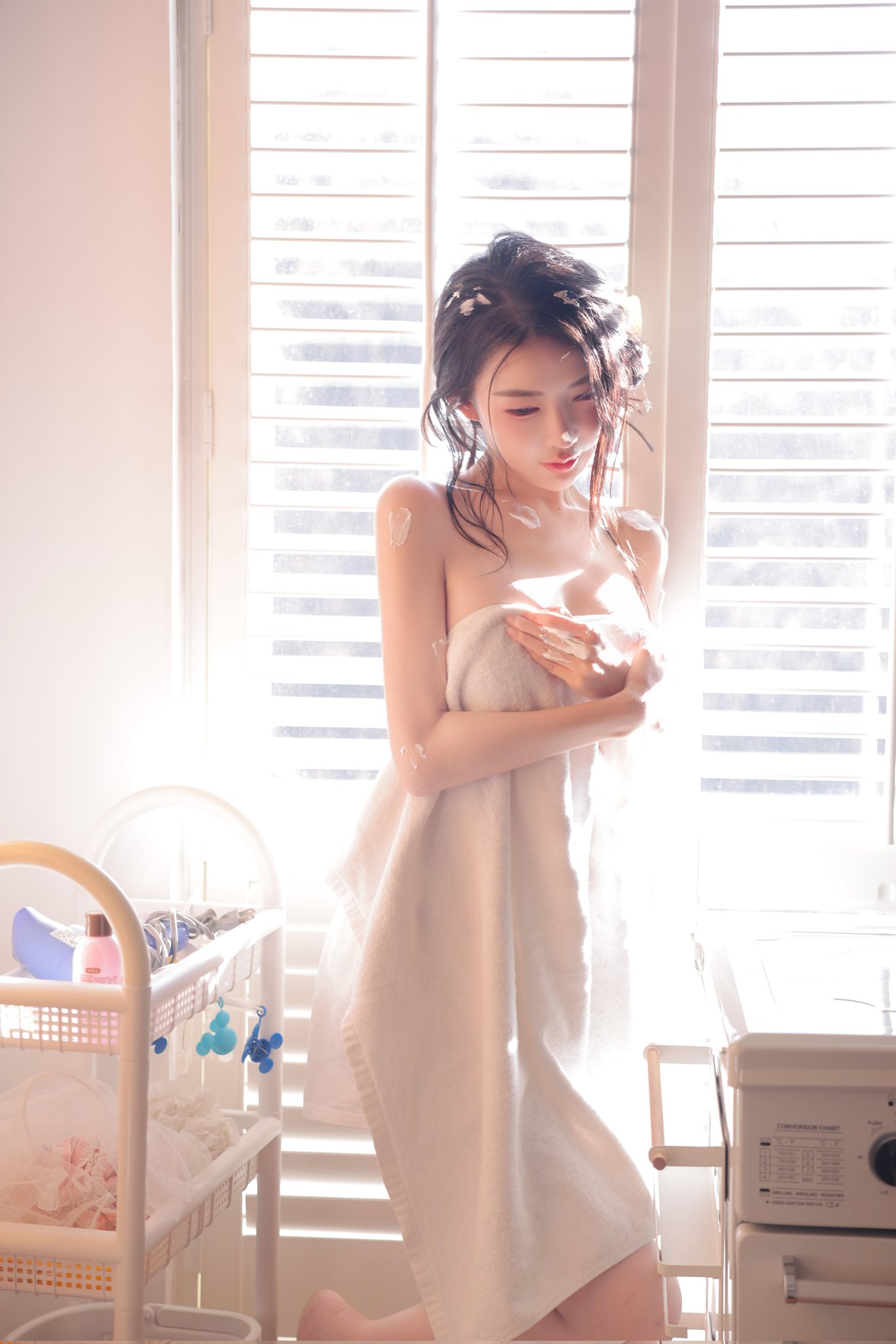 穿白毛巾的女人坐在洗衣机前面。