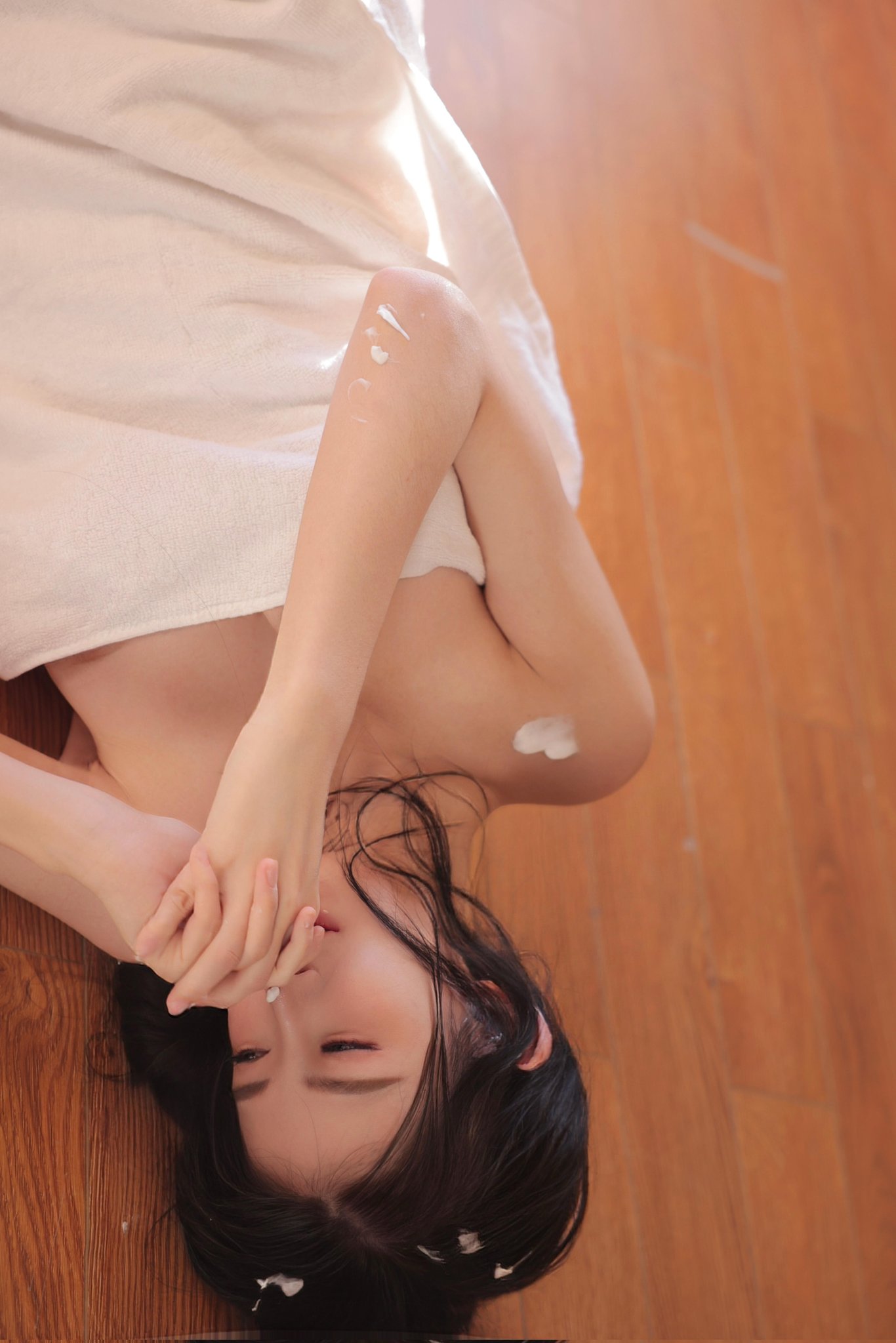 穿白毛巾的女人坐在洗衣机前面。