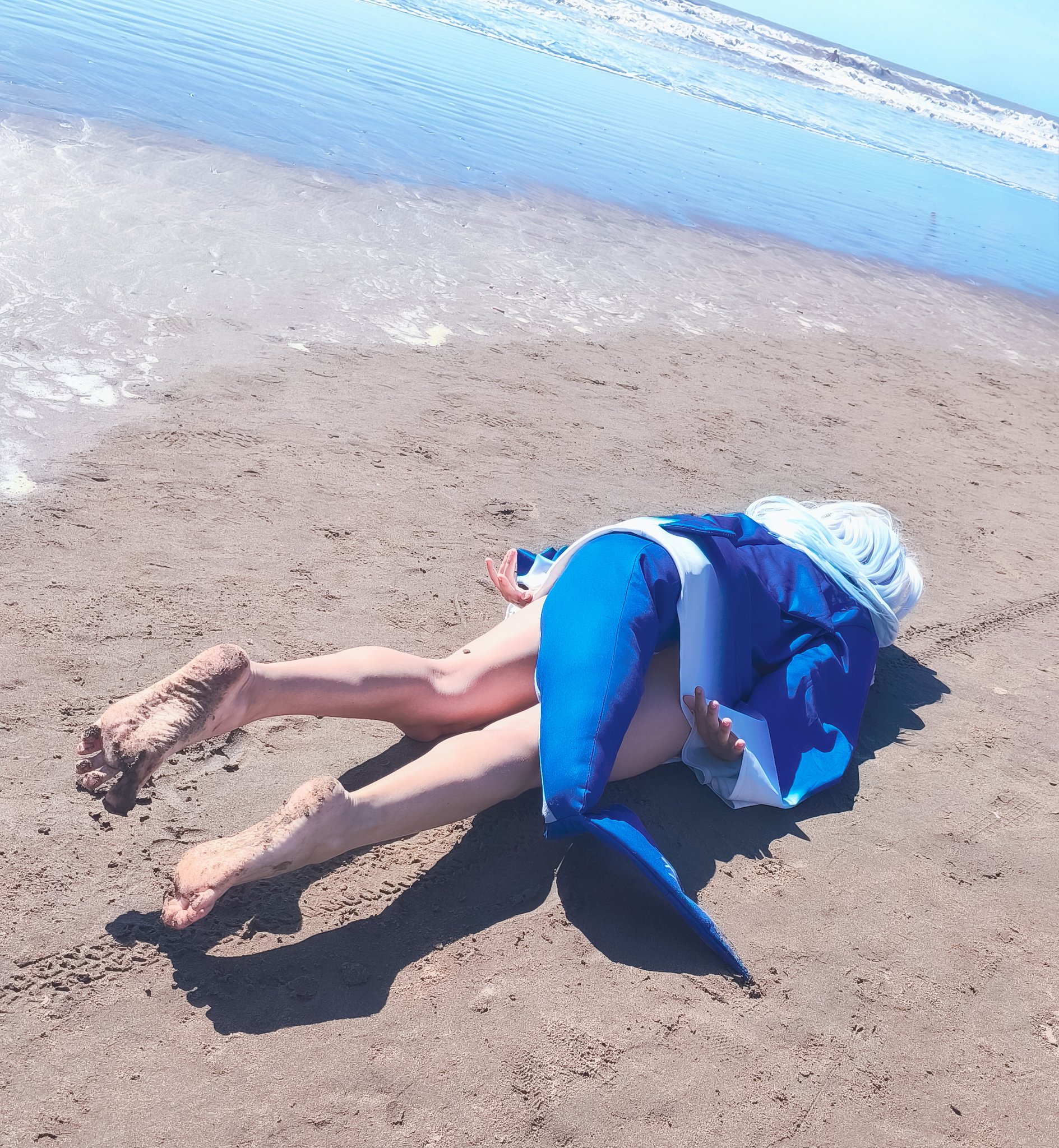 人躺在海滩上,身着蓝色衬衫和蓝鲨鱼。