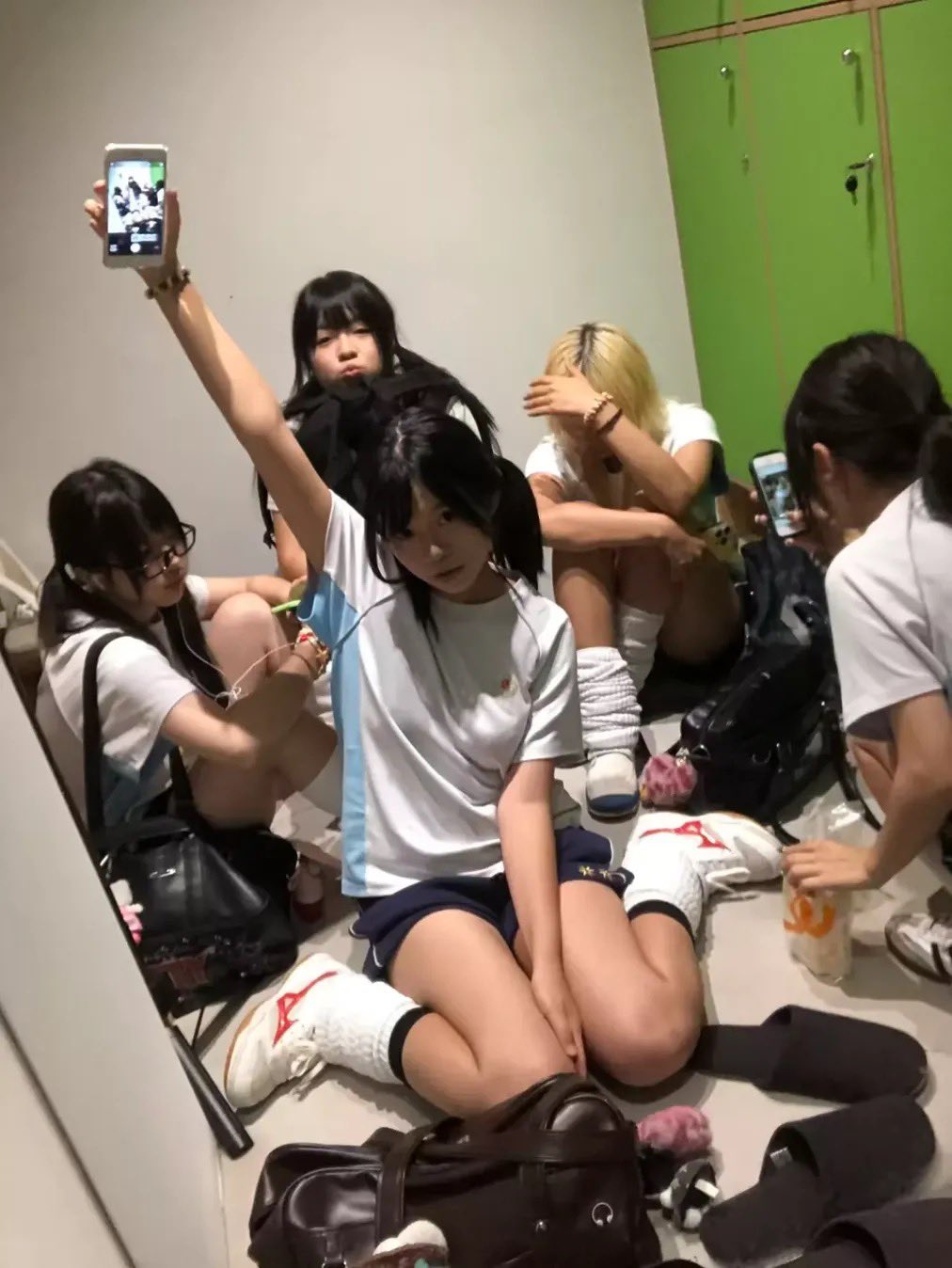 一群妇女坐在地板上,其中一人拿着手机。