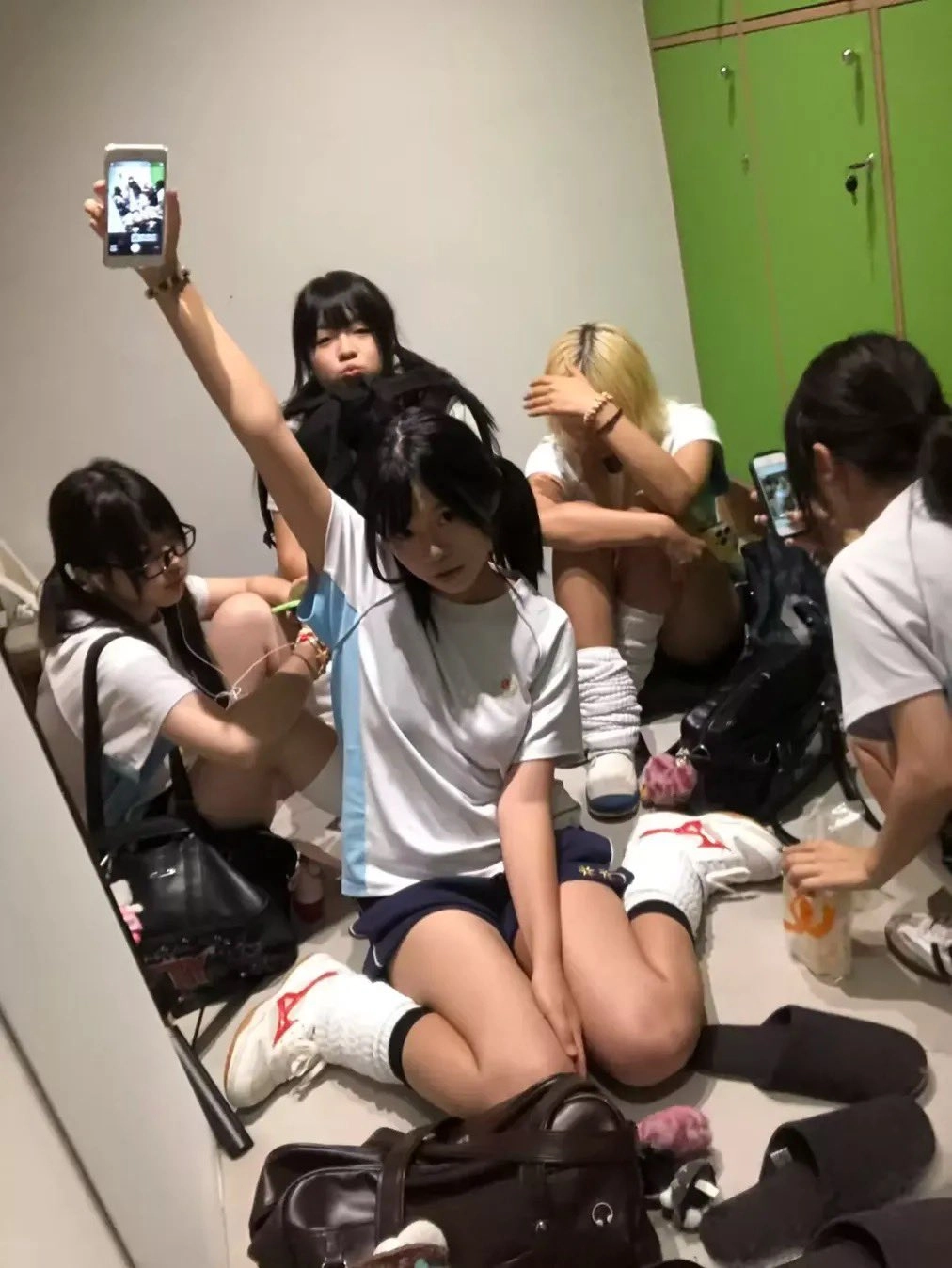 一群妇女坐在地板上,其中一人拿着手机。