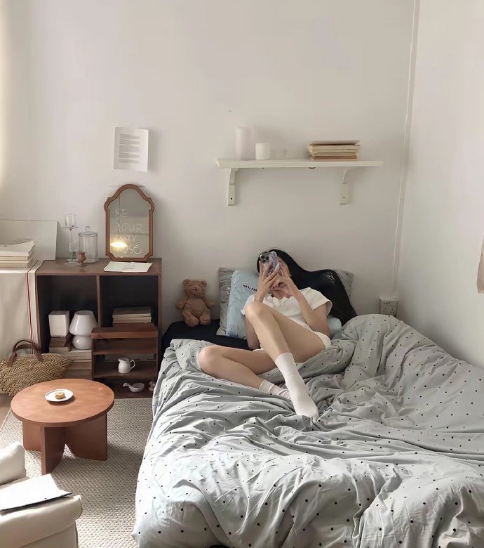 女人躺在一张床上,和一只泰迪熊在一起。