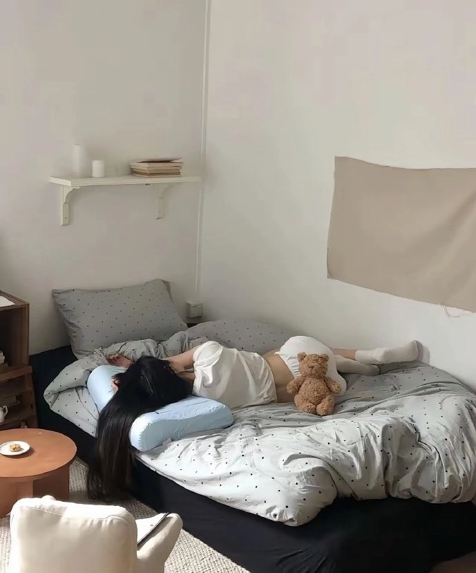 女人躺在一张床上,和一只泰迪熊在一起。