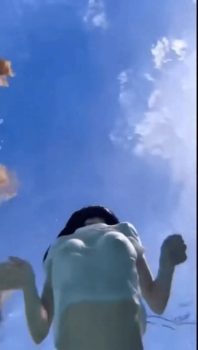 一位穿着白色衬衫和黑色头发的女人在海里游泳。