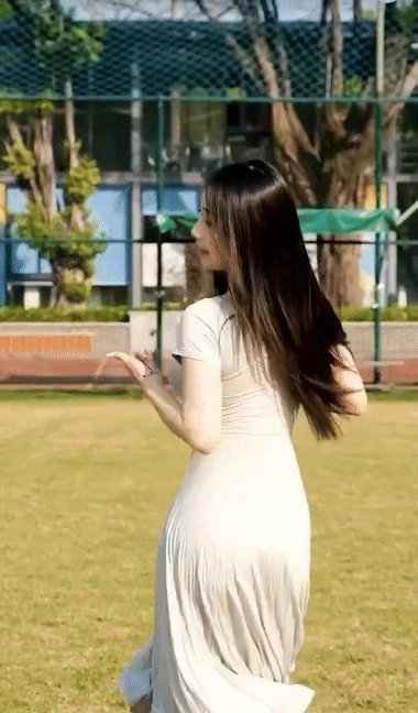 一位长发、白衣的妇人站在田野上。