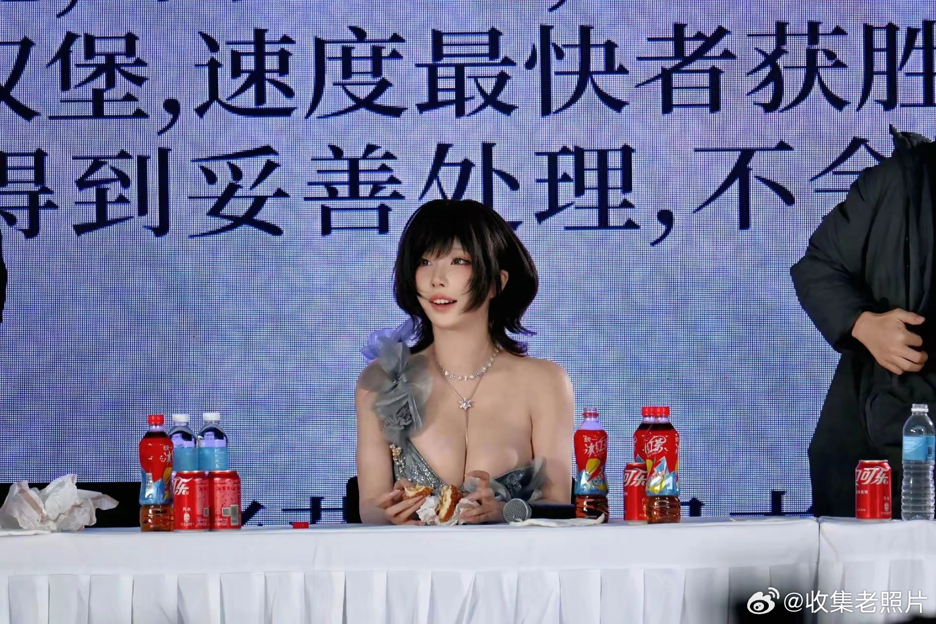 女人坐在一张桌子上,拿着一顿三明治和饮料。