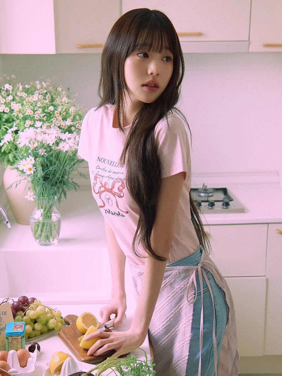 穿着粉红色衬衫的女孩站在厨房里。