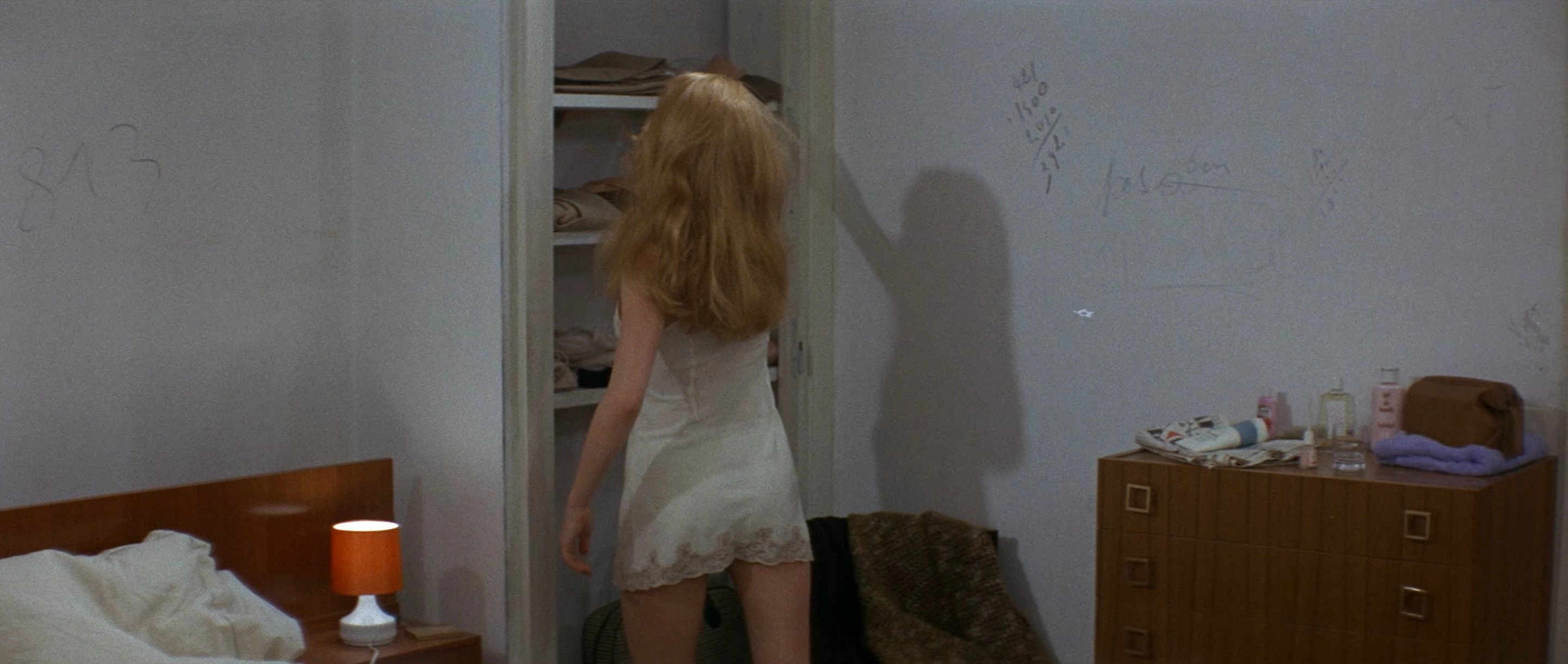 穿着白色衣服的女人看着一个衣柜。