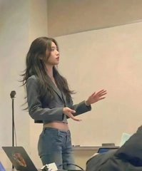 一位穿着黑色夹克和牛仔裤的女人正在做演讲。