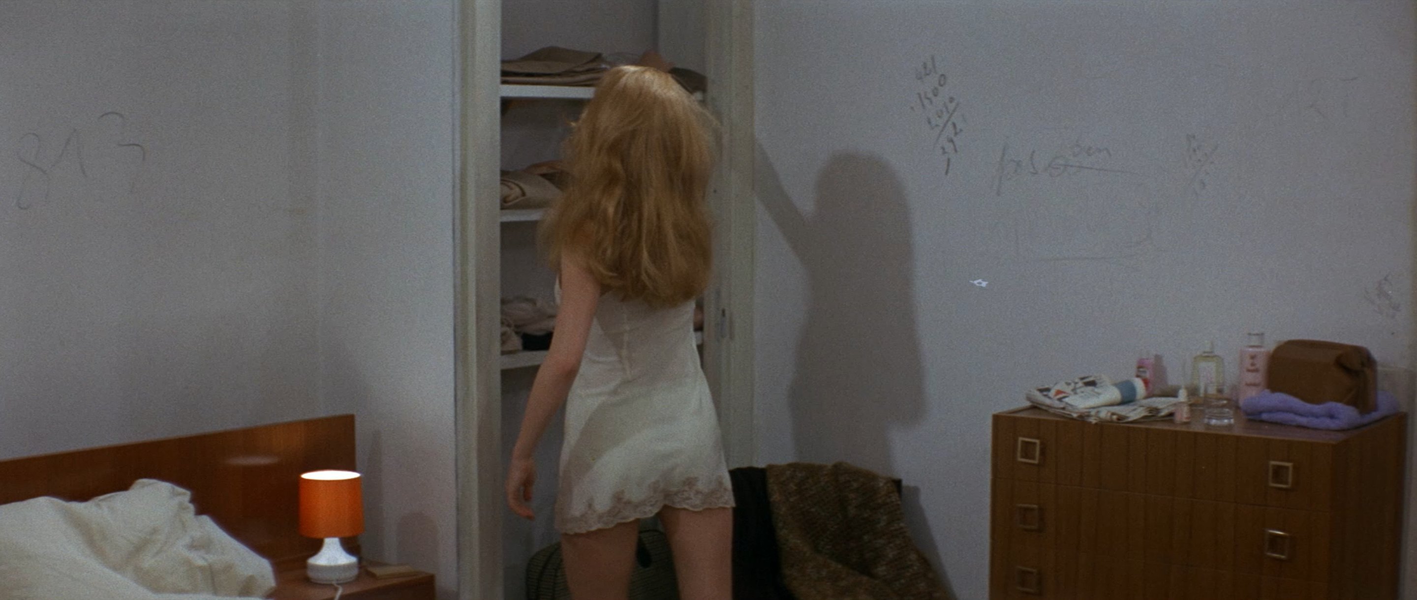 穿着白色衣服的女人看着一个衣柜。