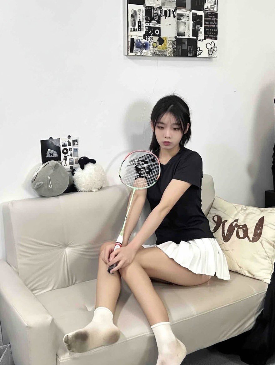 女人坐在沙发上,拿着一根网球架。