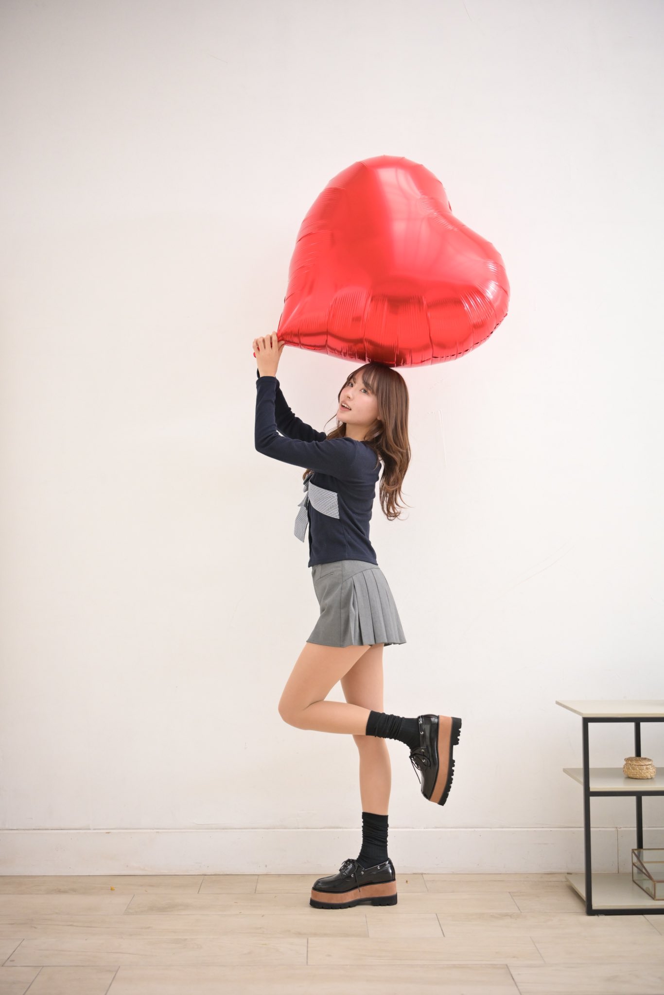 女人拿着一颗巨大的红色心脏气球。