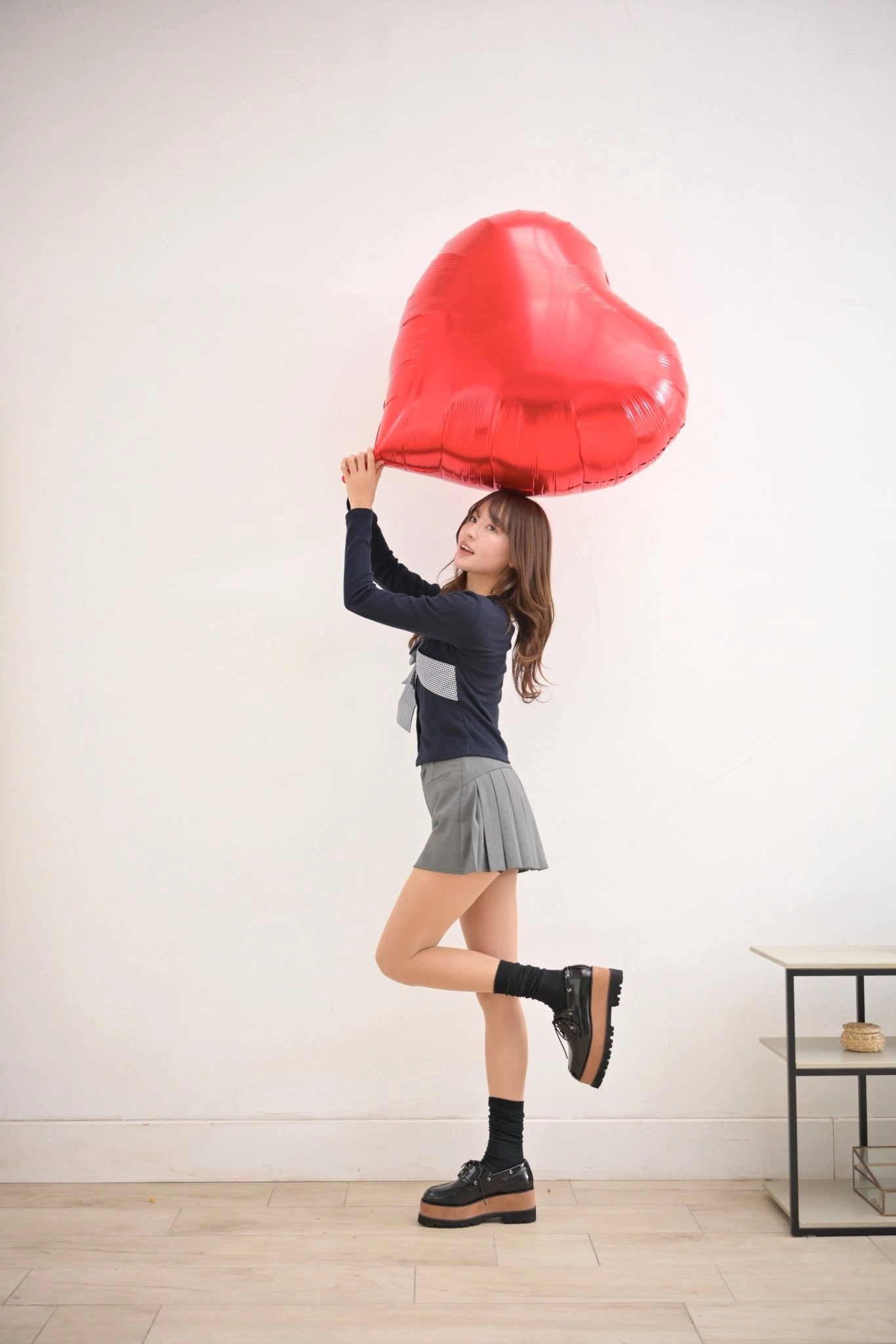 女人拿着一颗巨大的红色心脏气球。