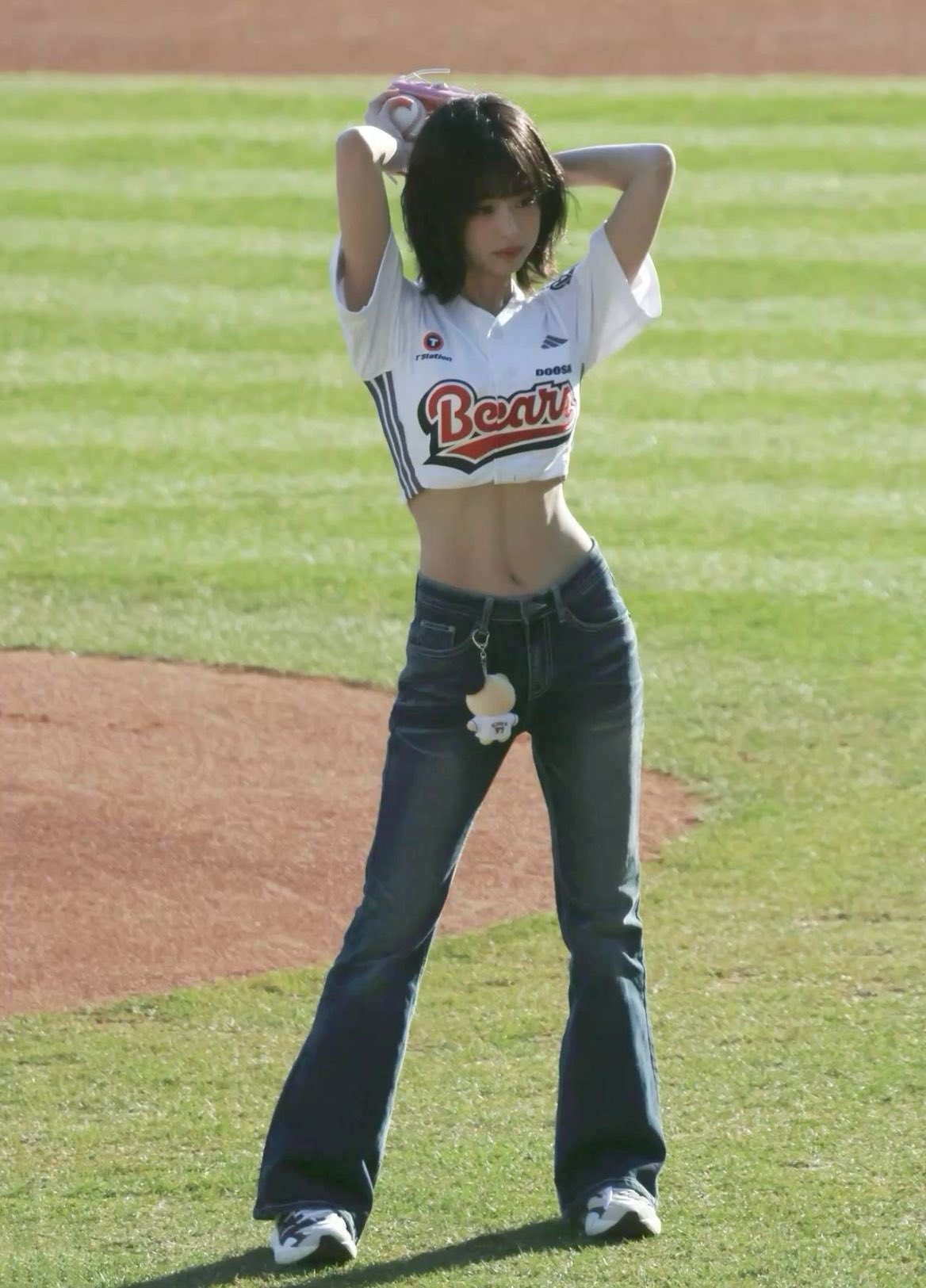 一位穿着白色衬衫和蓝色裤子的女人站在棒球场上。