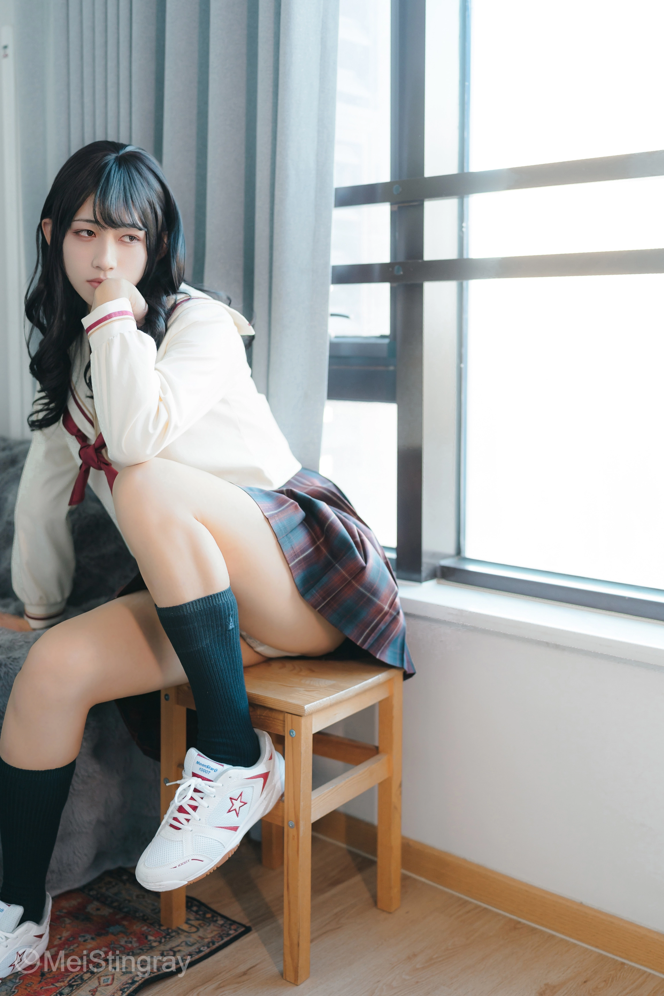 穿着白色夹克和一件白色裙子的女孩坐在椅子上。