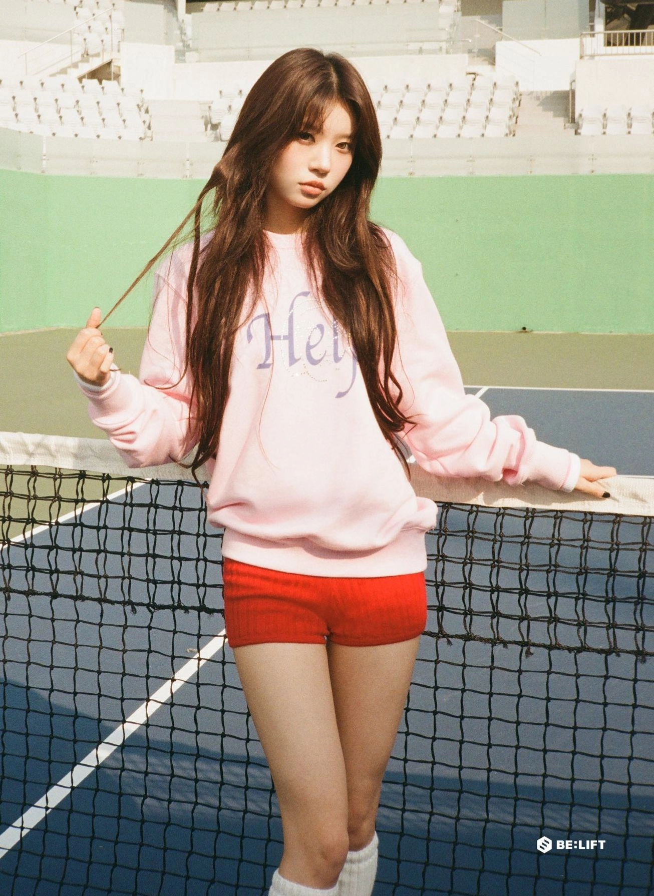 一位穿着粉红色衬衫和红色短裤的女人站在网球场上。