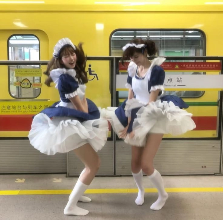 两个女士穿着女仆服装在地铁平台上跳舞。