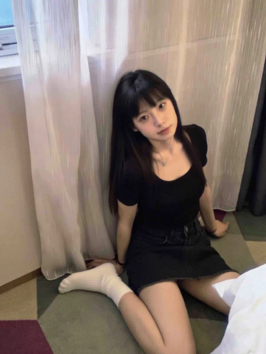 穿着黑色衬衫和黑色短裤的女人坐在地板上。