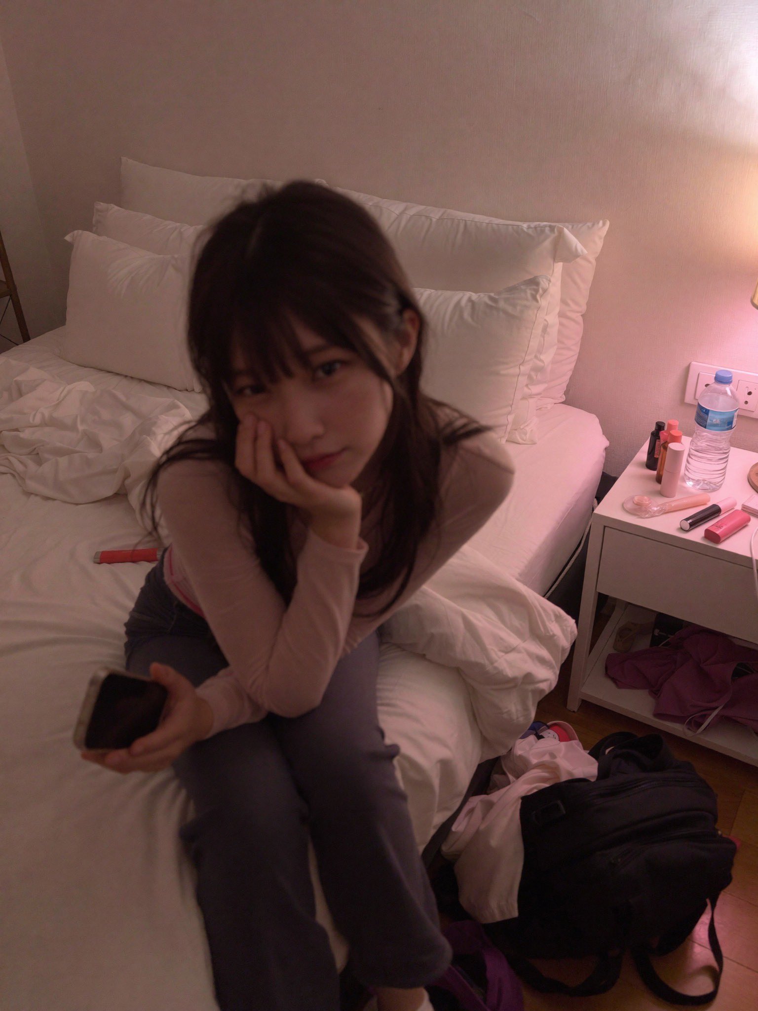 女人坐在床上,手里拿着手机。