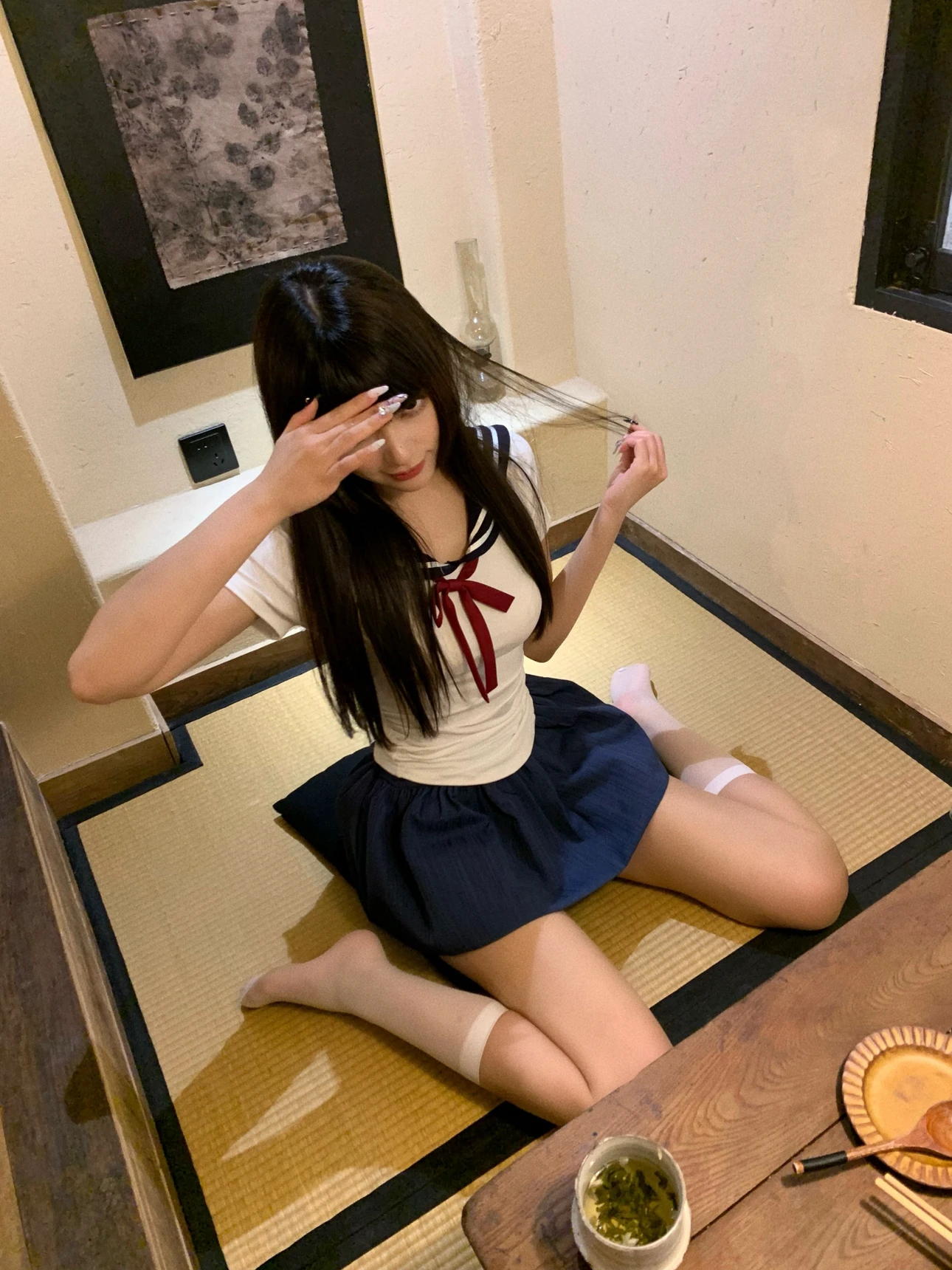 戴着一个水手的帽子和一个红色的弓的女孩坐在地板上。