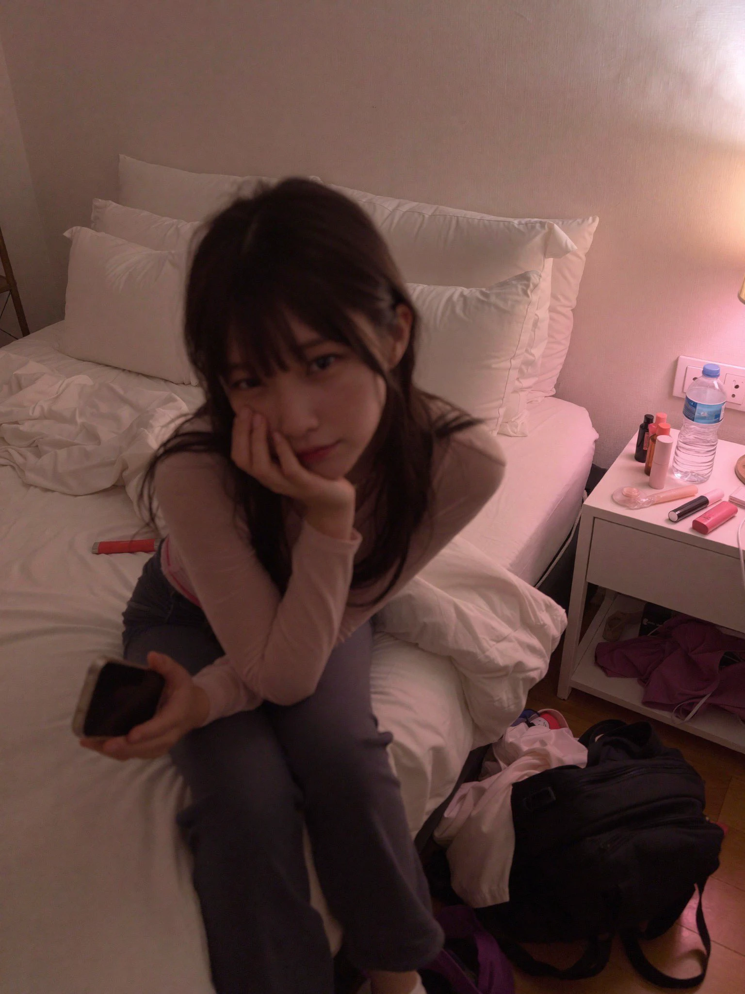 女人坐在床上,手里拿着手机。