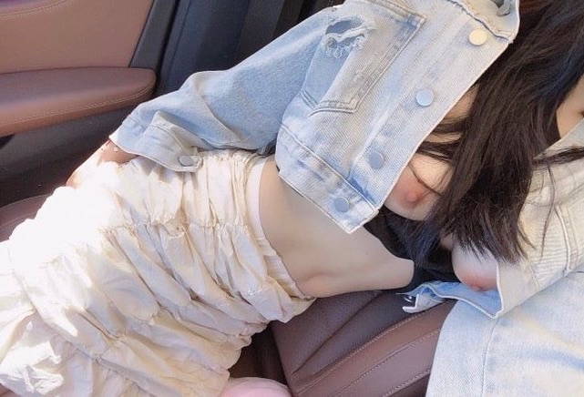 穿着蓝色夹克的女人躺在汽车座位上。