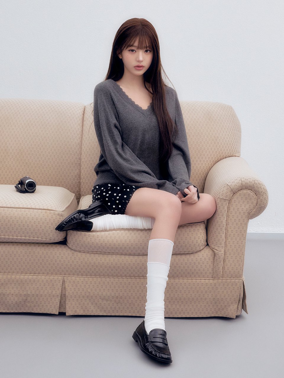 穿着灰色衬衫和黑色鞋子的女人坐在沙发上。