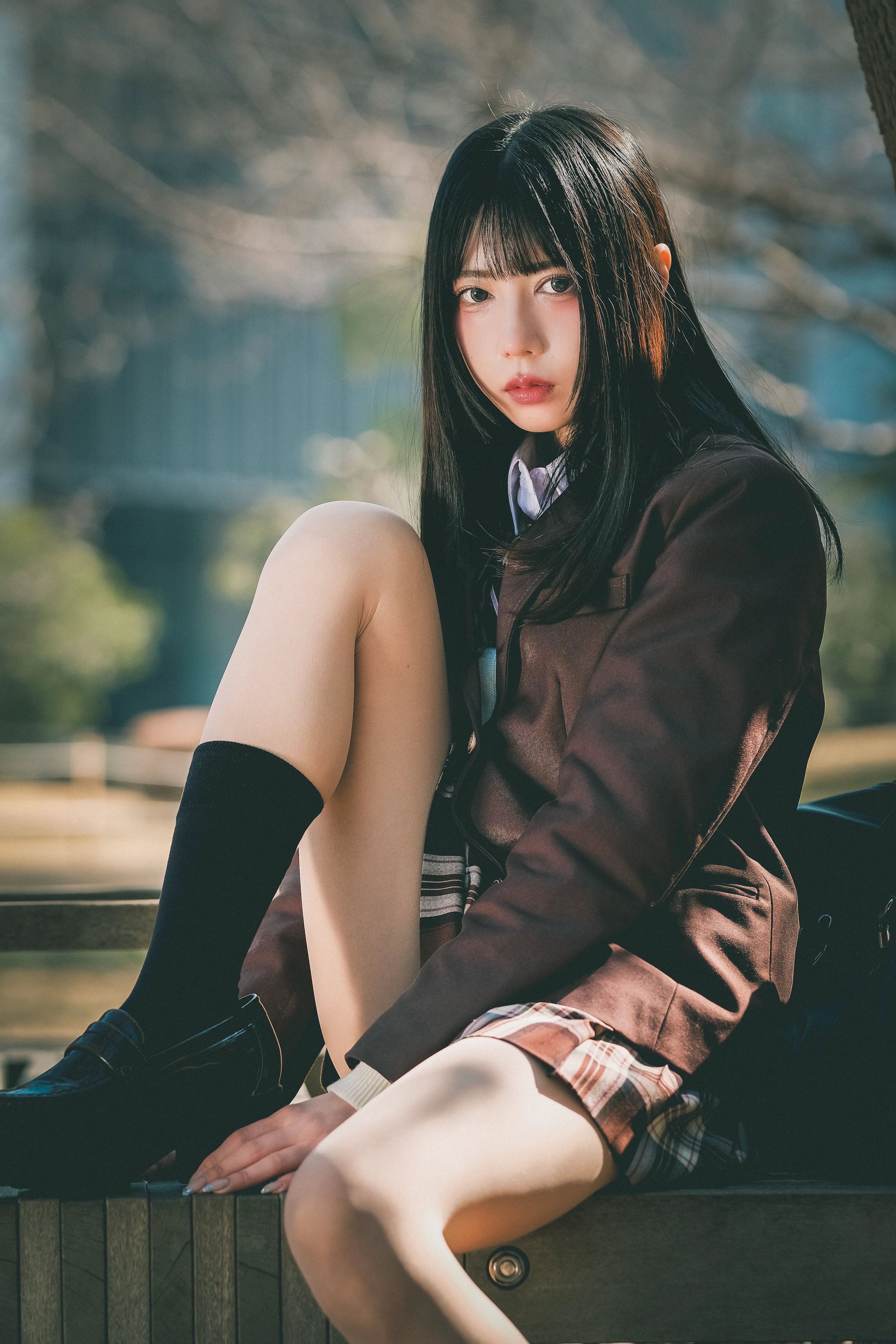 穿着棕色夹克和黑色袜子的女孩坐在一个凳子上。