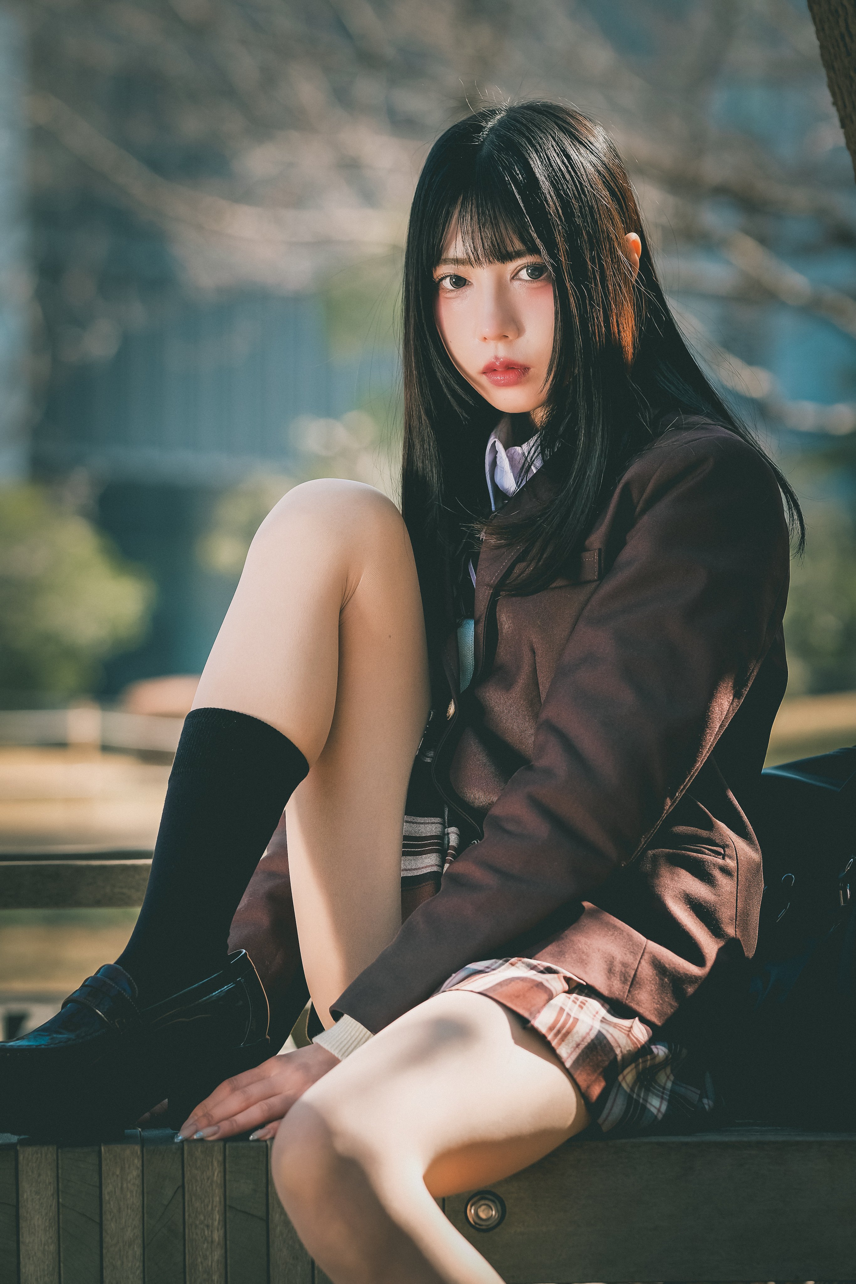 穿着棕色夹克和黑色袜子的女孩坐在一个凳子上。