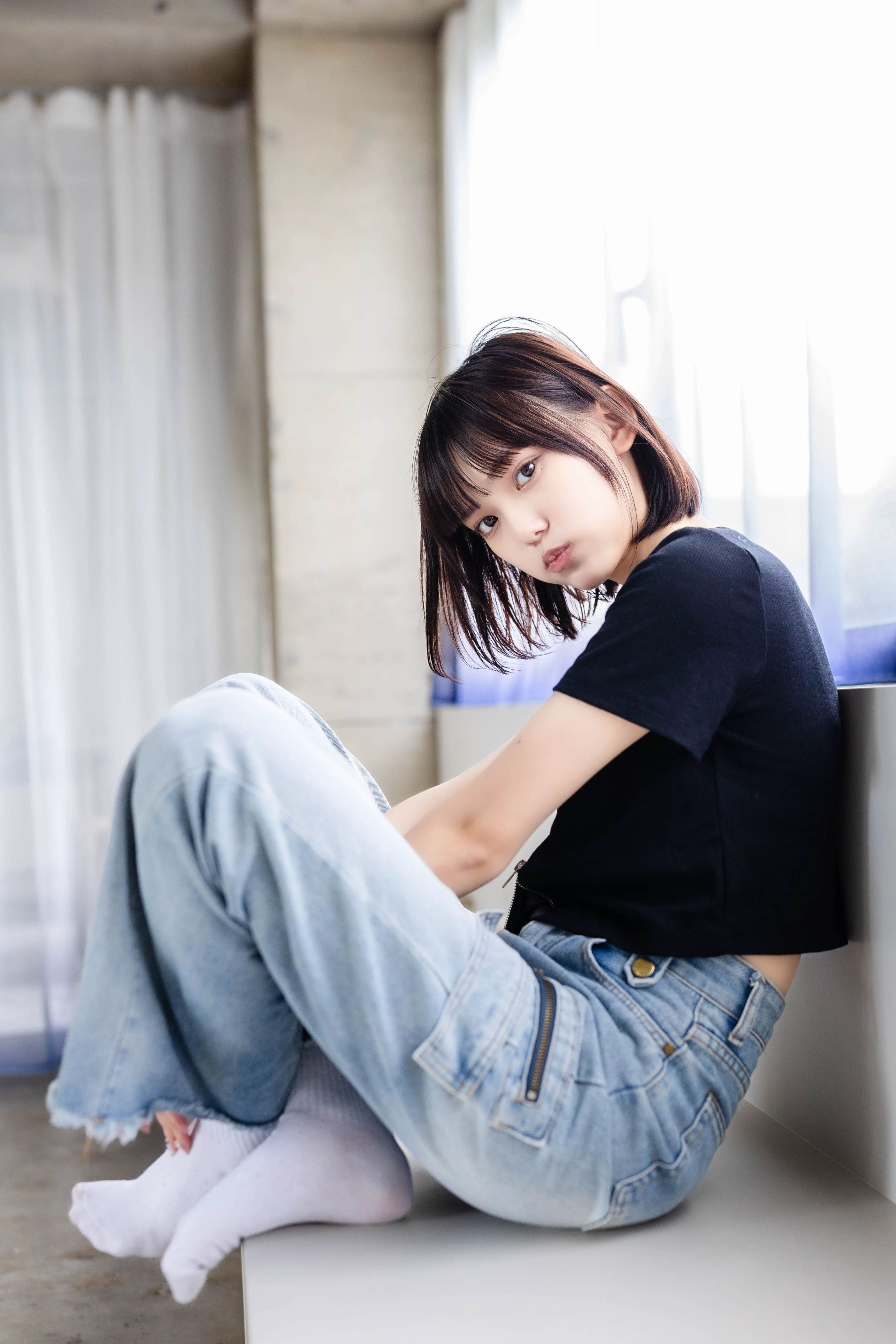 长头发和一件黑色衬衫的女人坐在一个凳子上。