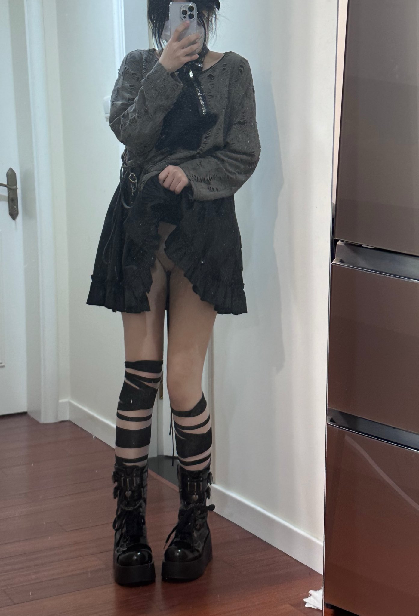 一位穿着黑色裙子和带条袜子的女人站在镜子前。