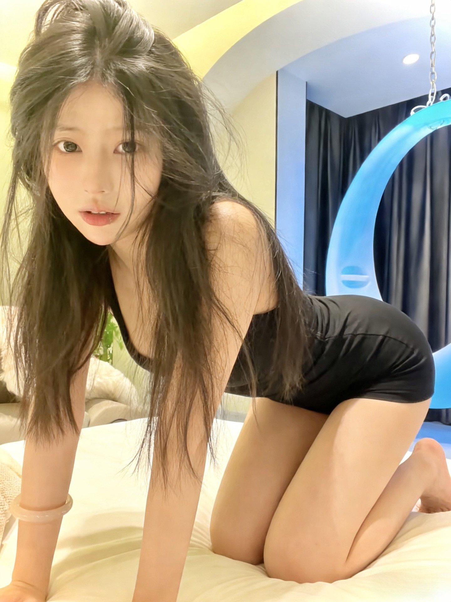 长头发和黑裙子的女人坐在床上。