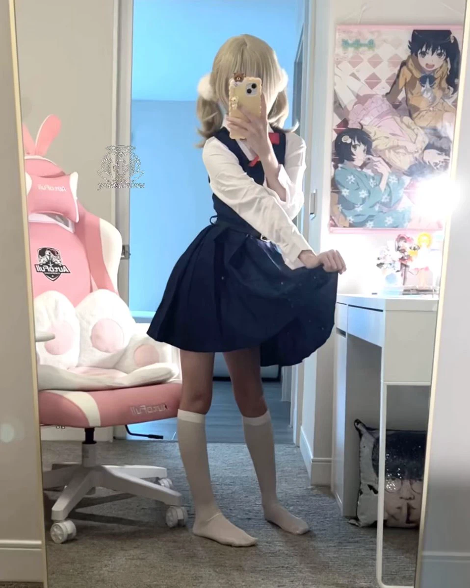 一位穿着蓝色裙子和白色袜子的女孩在镜子前拍了一张自拍。