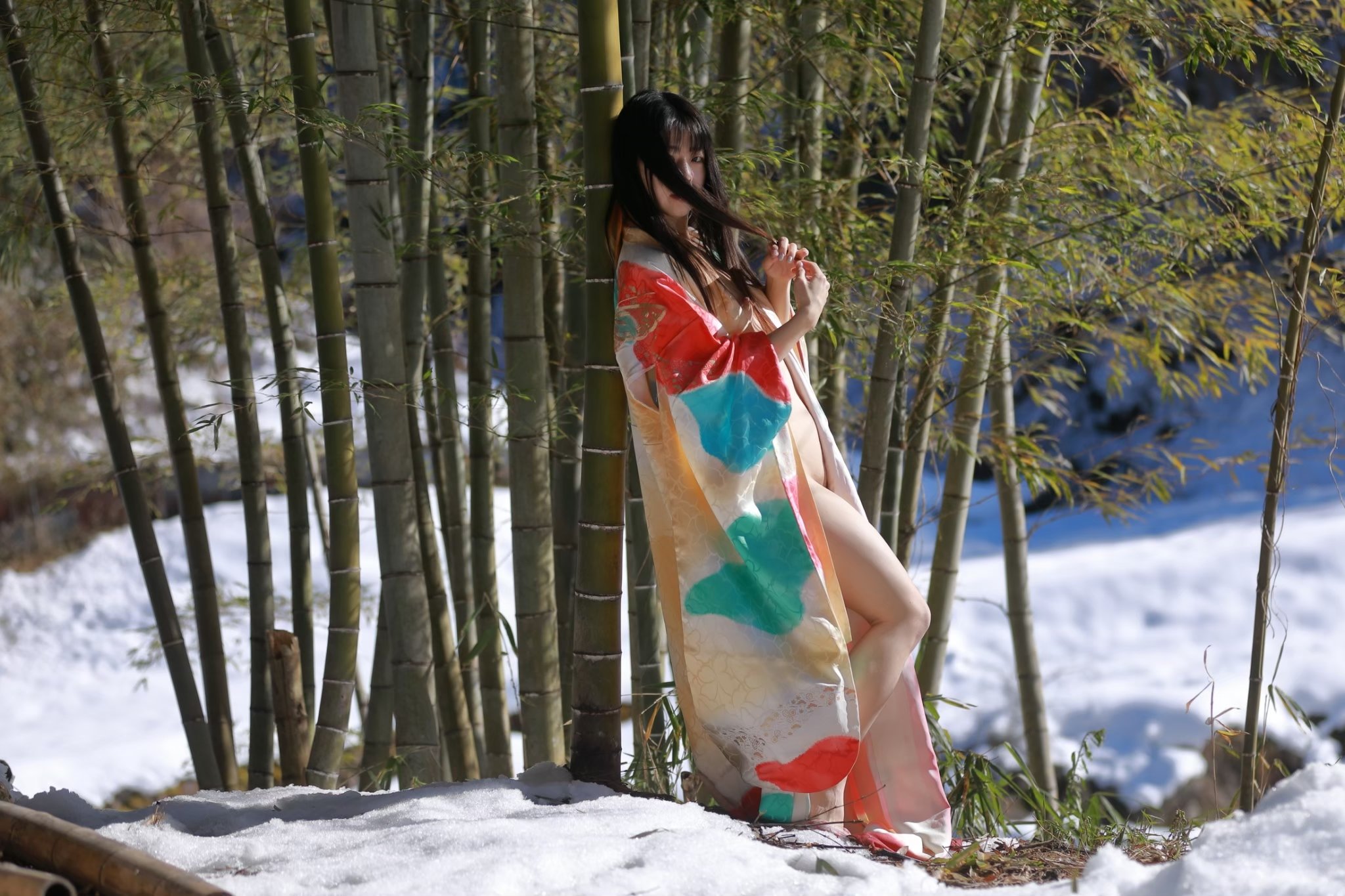 穿着彩色吉莫诺的女人站在雪地上。