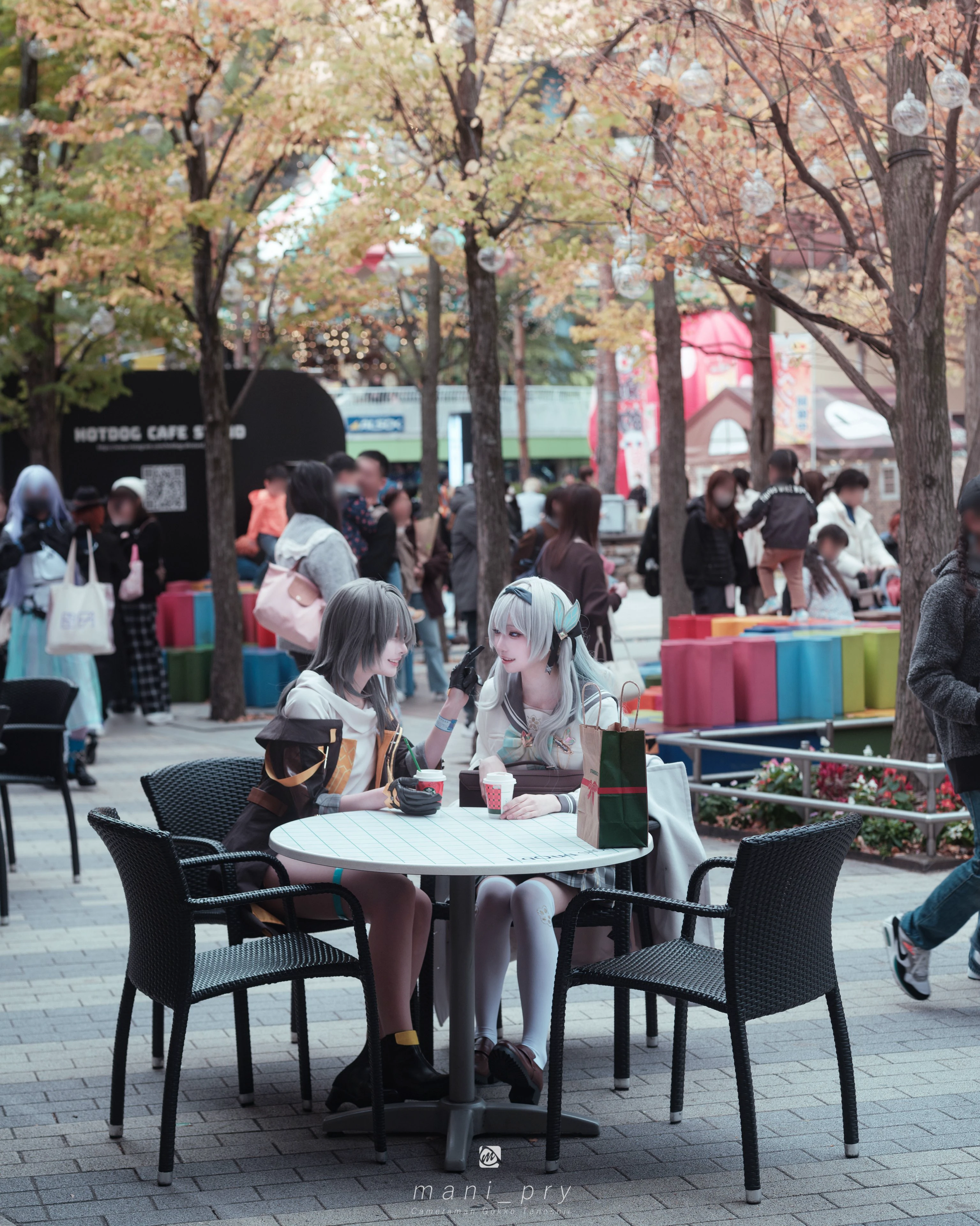 两个女人坐在拥挤的公园的桌子上。