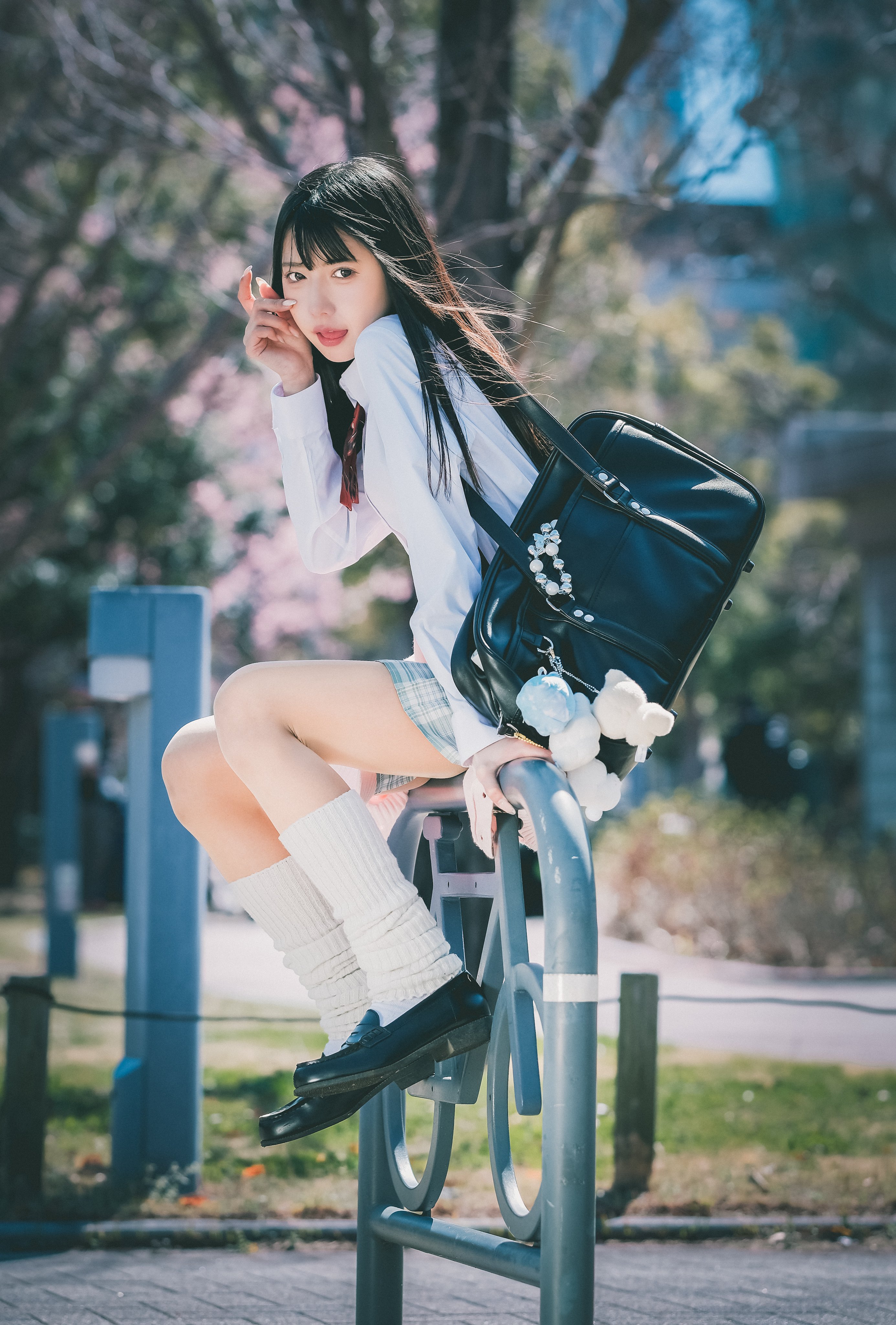 女孩背着一个背包,坐在一个杆子上。