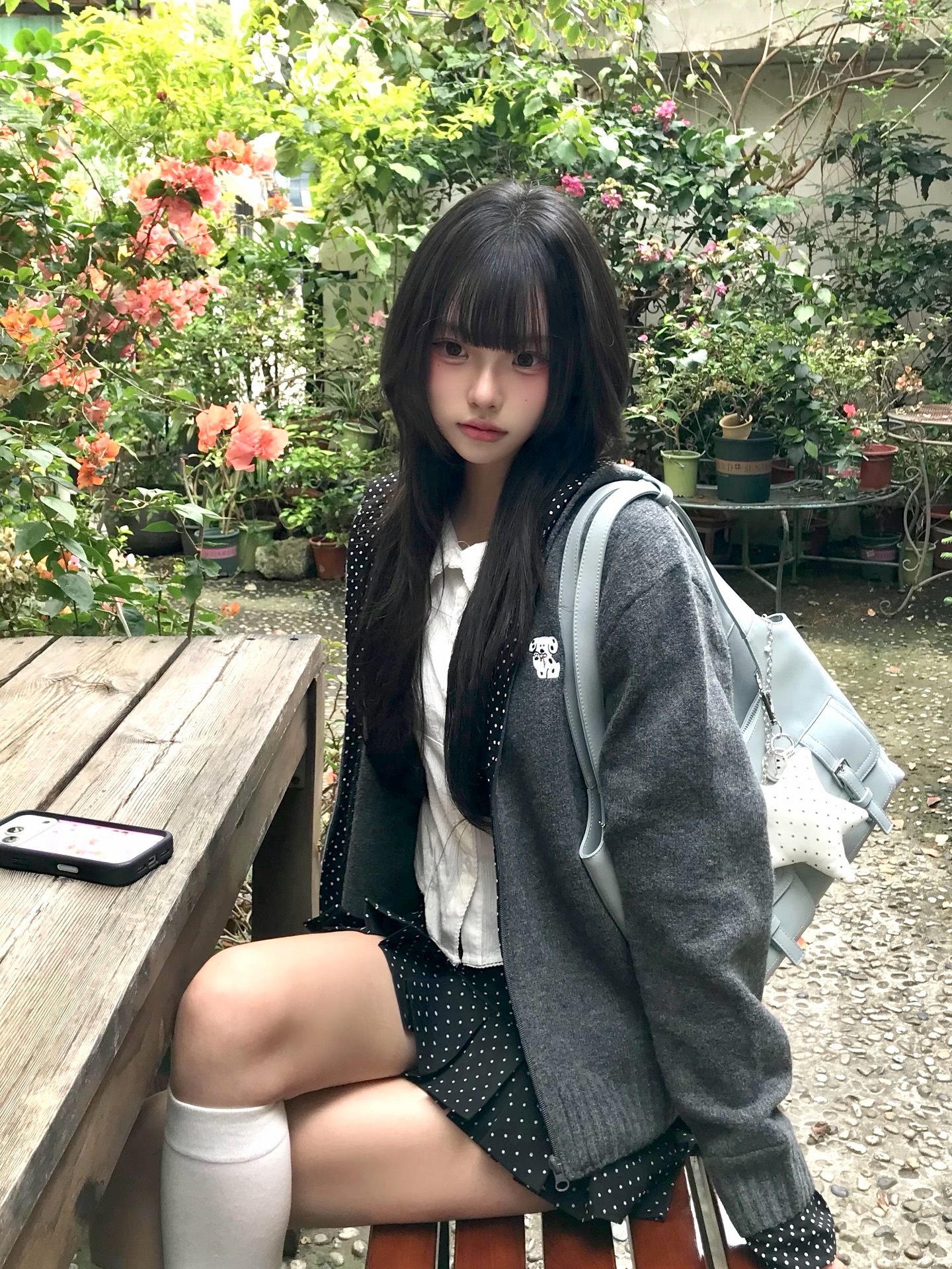 一位穿着波尔卡点裙和灰色衬衫的女人坐在凳子上。