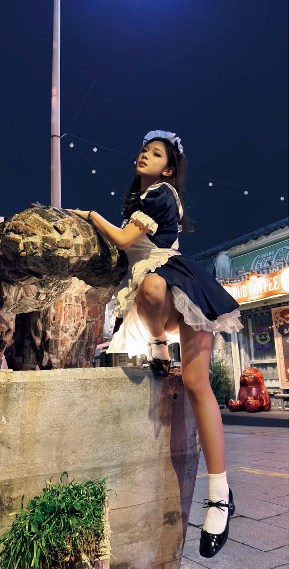 穿着女仆服的女人爬上一座雕像。