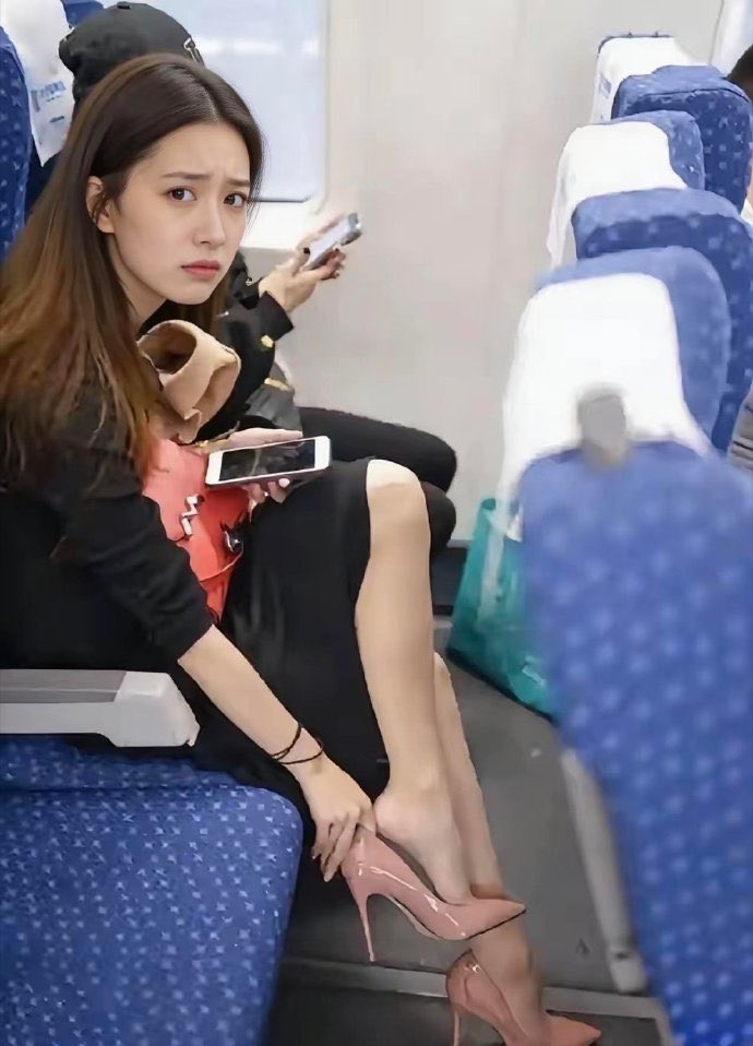 穿着粉红色的鞋子的女人坐在飞机上。