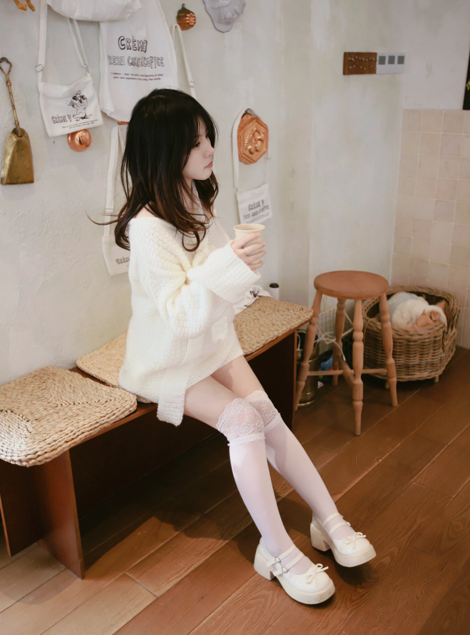 穿着白色衬衫和白色裤子的女人坐在一个凳子上。