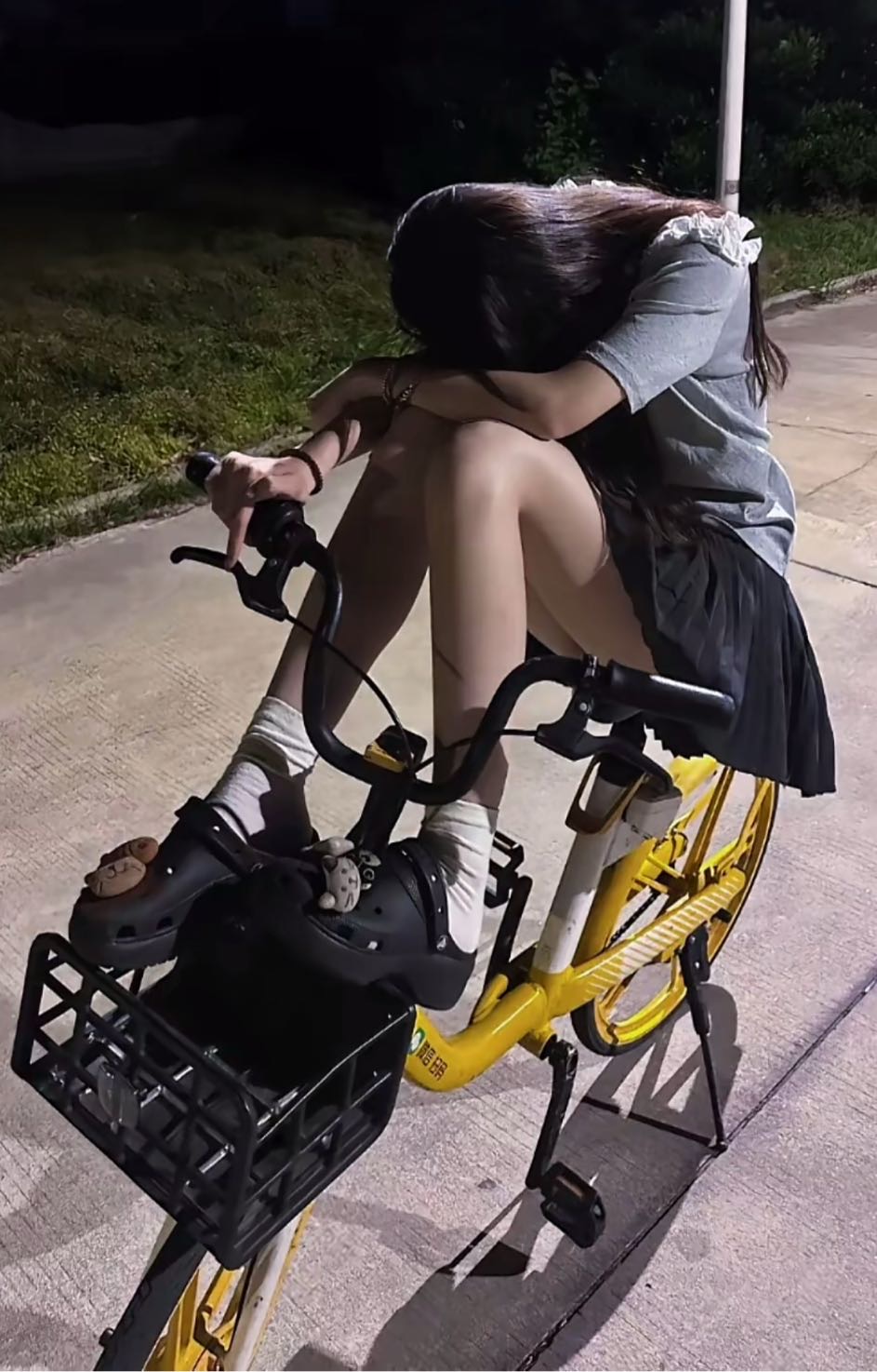 女孩坐在黄色的自行车上,她的头在膝盖上。