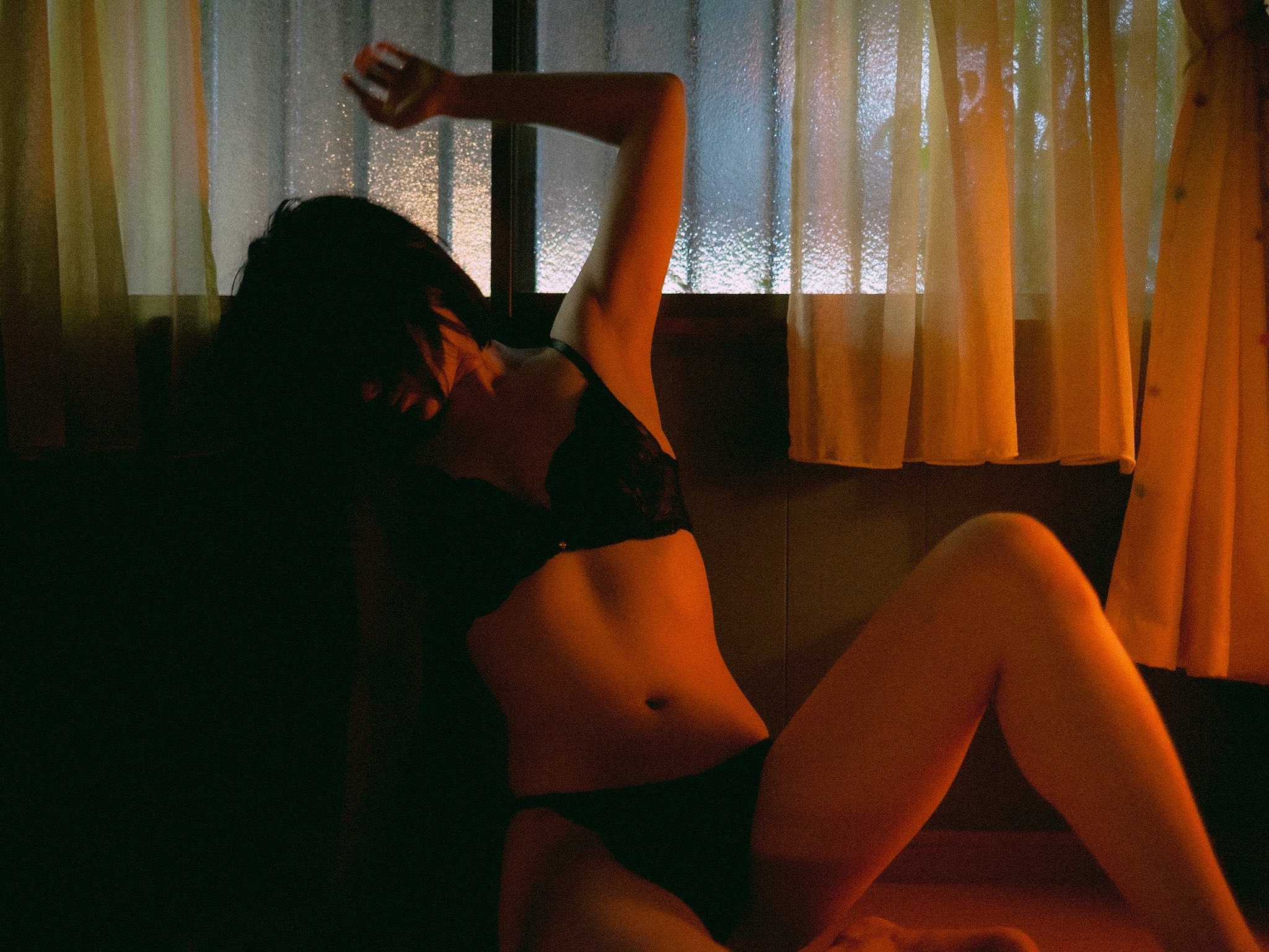 穿着黑色胸罩和裤子的女人躺在地板上。