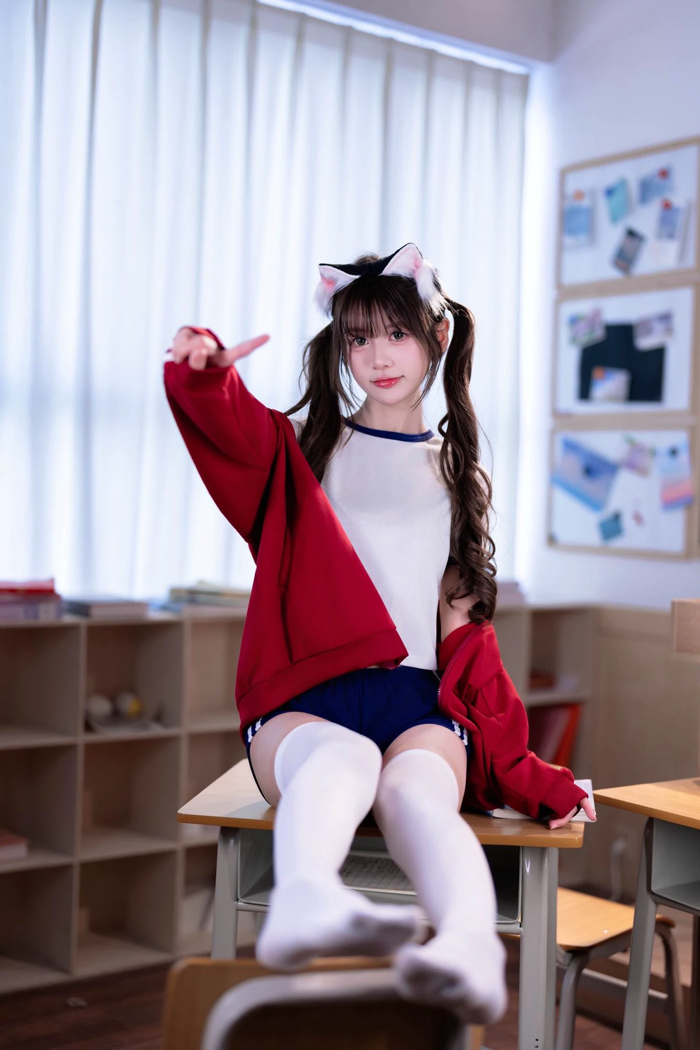 一位穿着红色衬衫和猫耳朵的女孩指向相机。