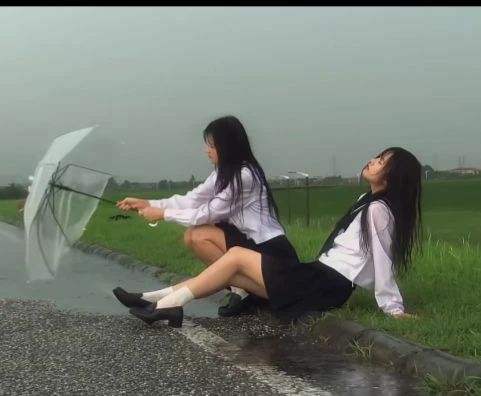 两个女孩坐在草地上,拿着伞。