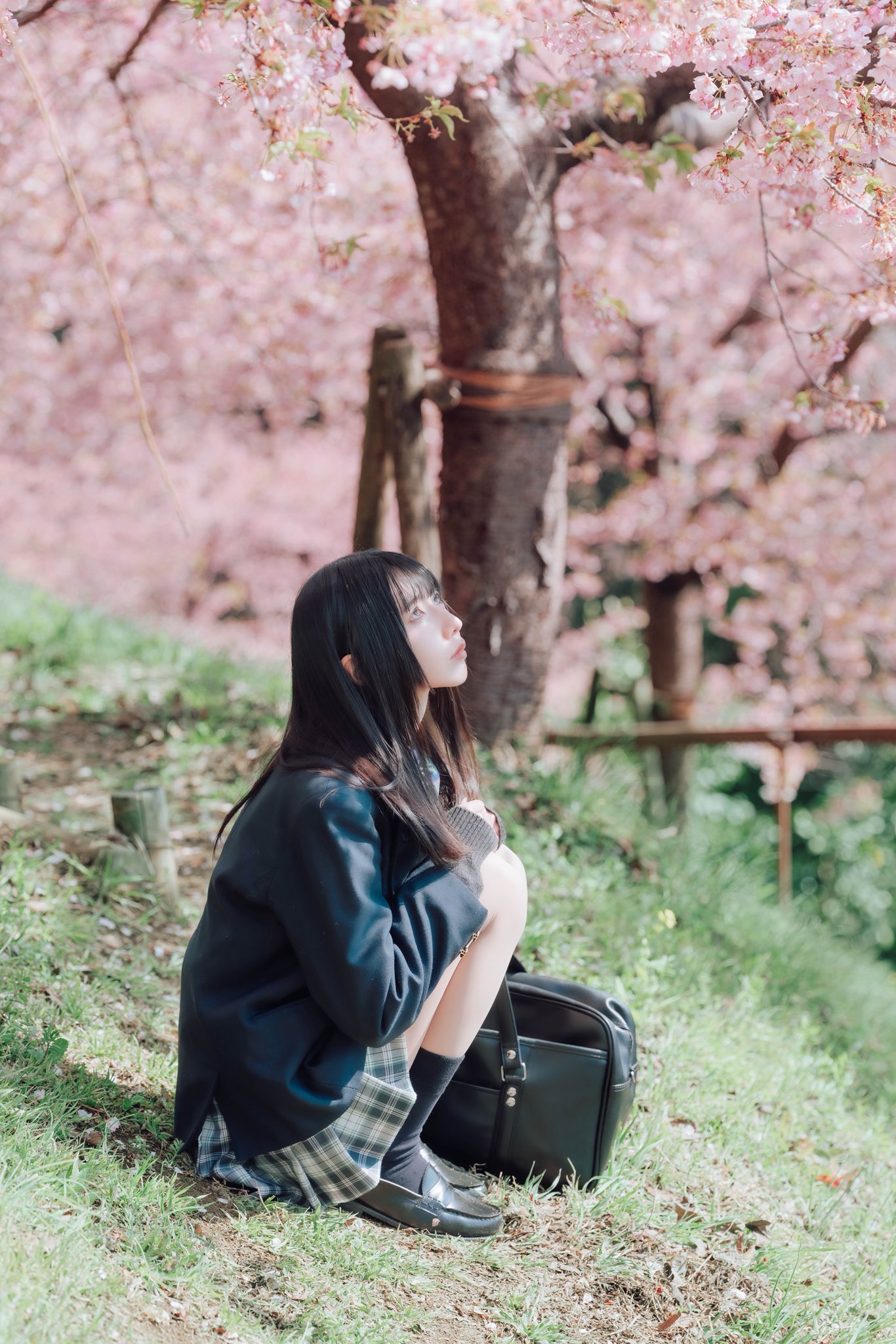 穿着黑色夹克和裙子的女人坐在地上。