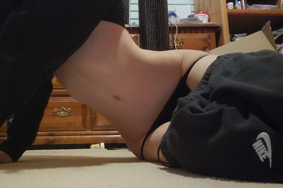 一位穿着黑色裤子和黑裤子的女人躺在地板上。