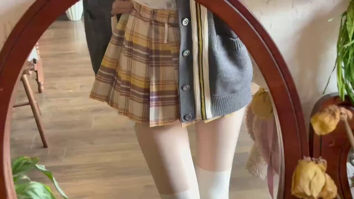 女人穿着一件白色裙子和一件灰色衬衫。