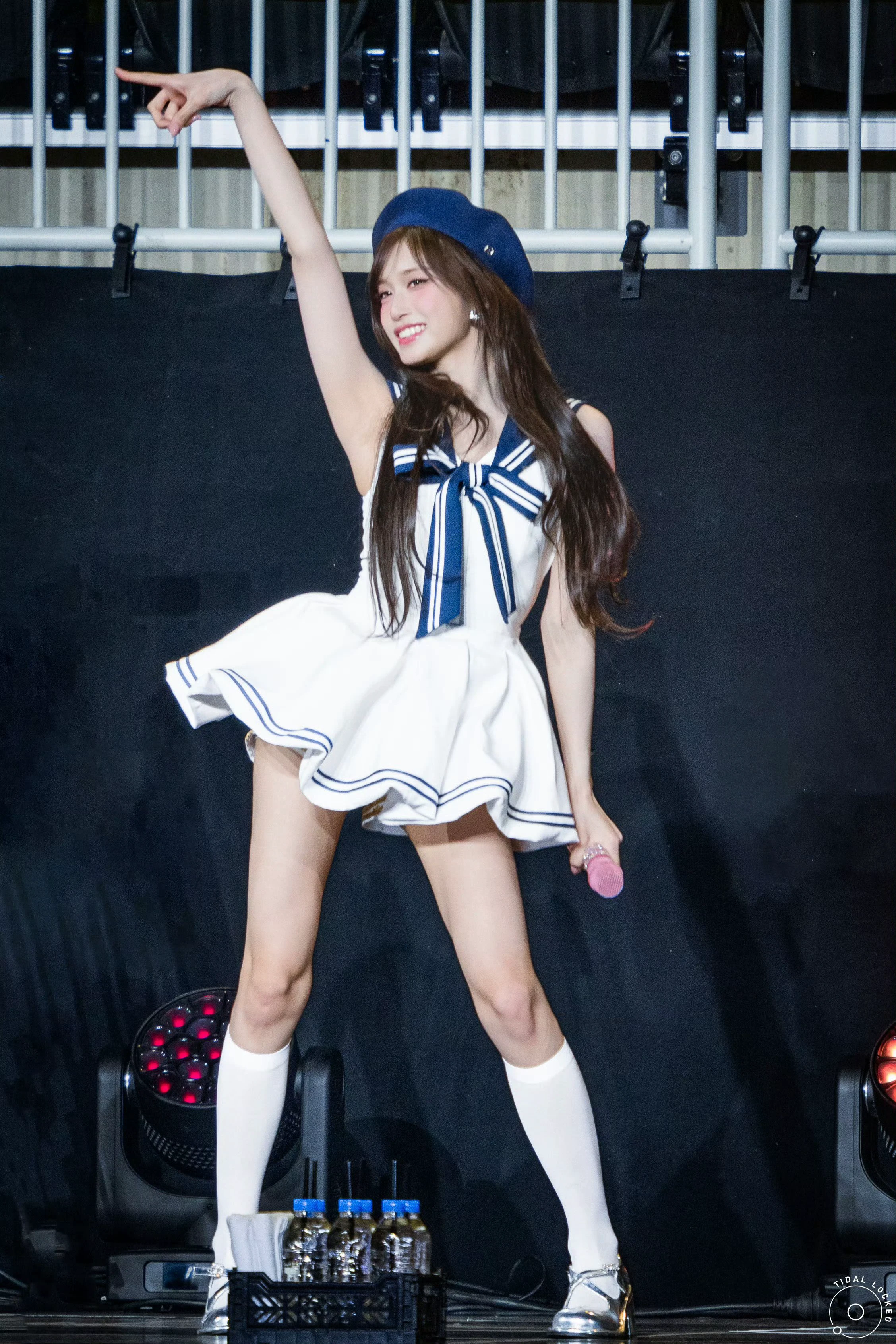 穿着水手的帽子和裙子的女人在麦克风里唱歌。