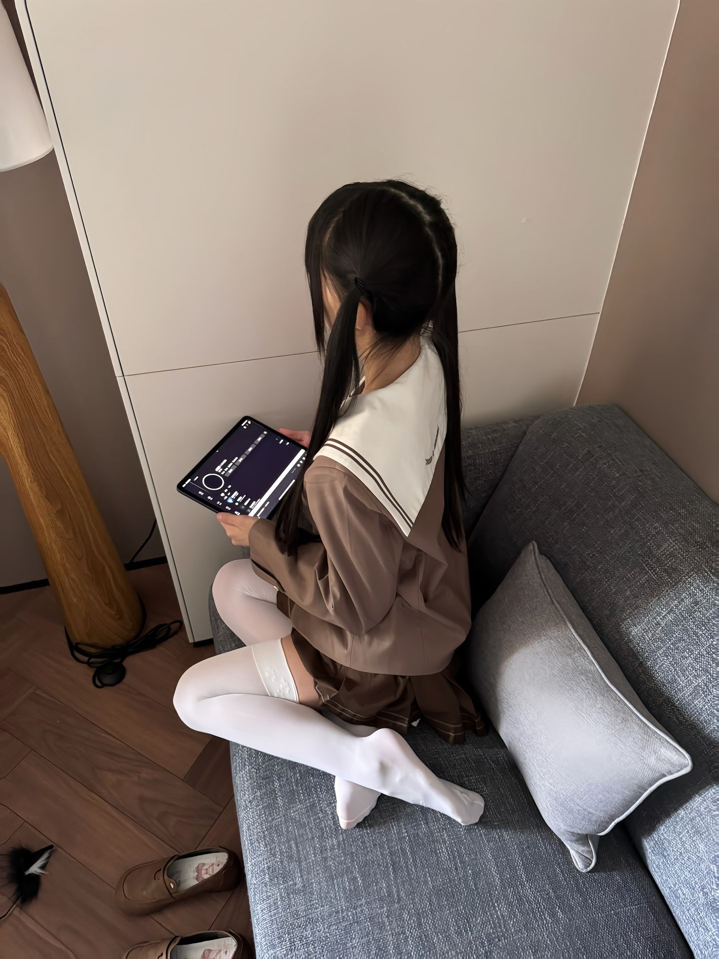 女孩捧着平板电脑坐在沙发上